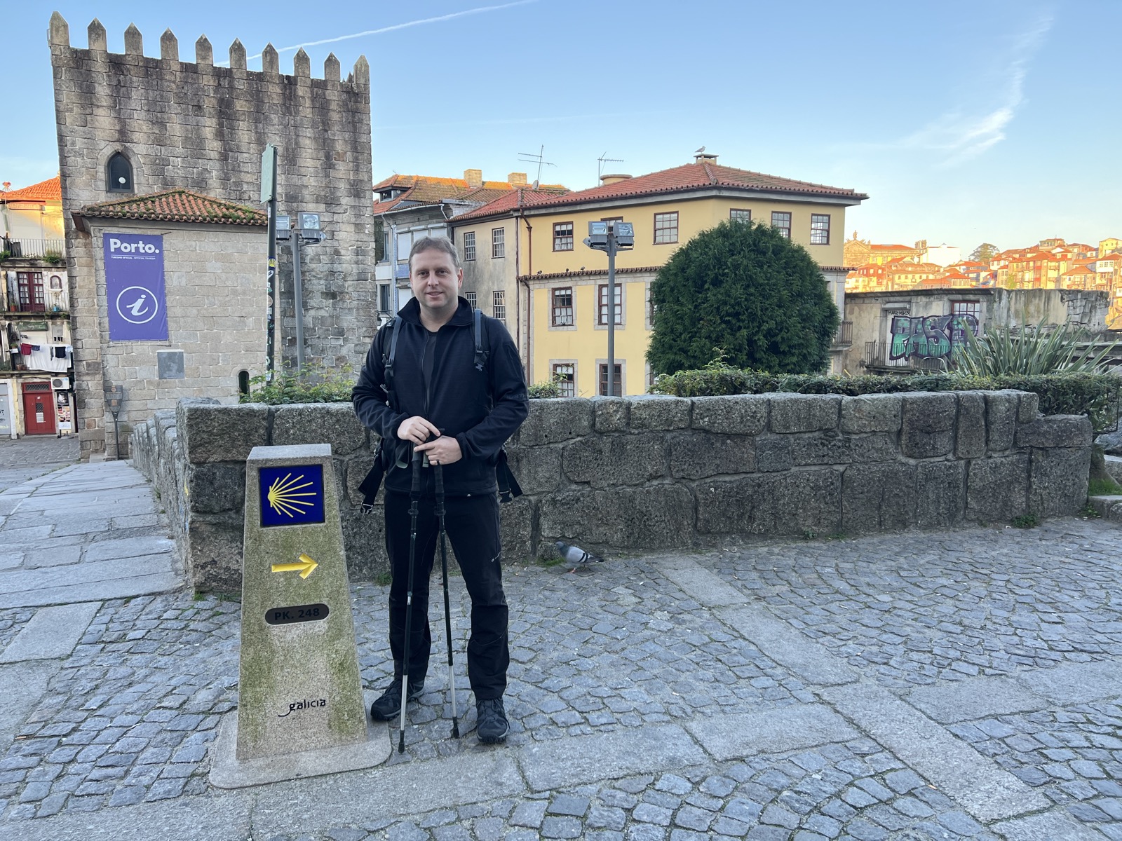 Kamenný mezník s mušlí a žlutou šipkou na startu Camino Portugués v centru Porta