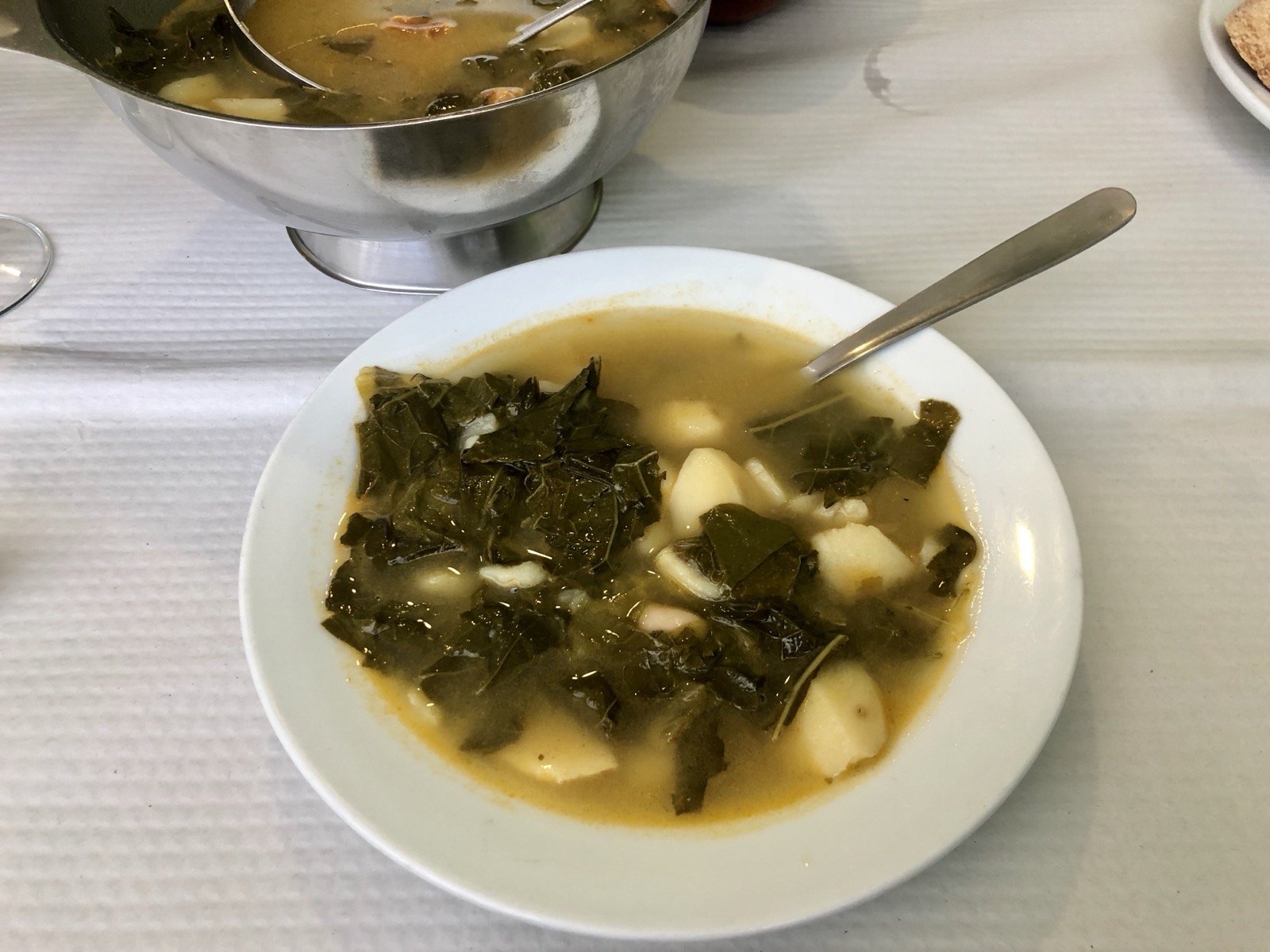 Talíř caldo gallego, galicijské polévky z brambor a zelených listů, jako první chod poutnického menu, vedle sklenka na víno