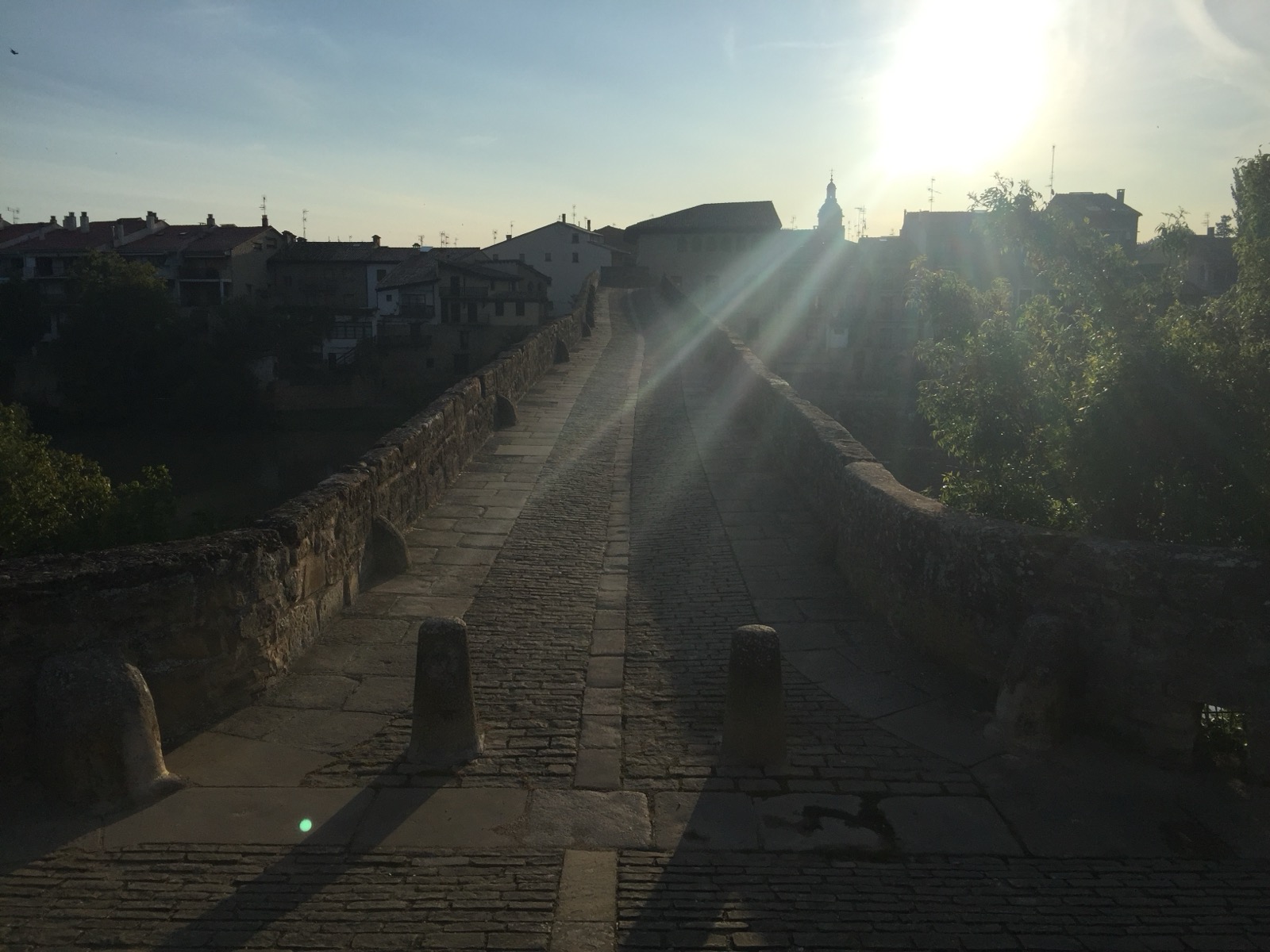 Prázdná kamenná cesta přes most do města za ranního protisvětla na Caminu