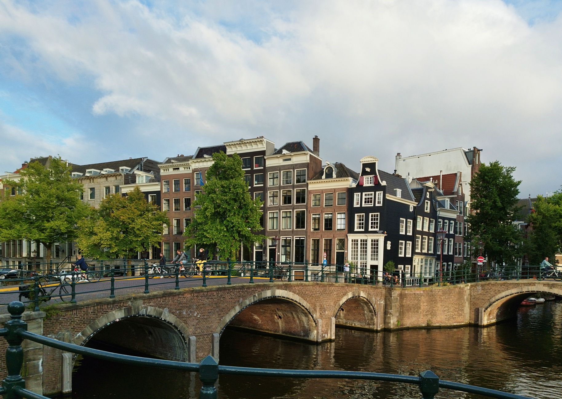 Pás kanálů Grachtengordel v Amsterodamu s historickými cihlovými domy a obloukovými mosty