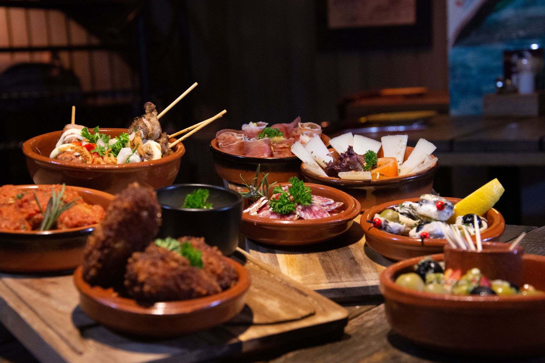 Talíř andaluských tapas s jamónem, olivami a smaženými rybičkami na baru