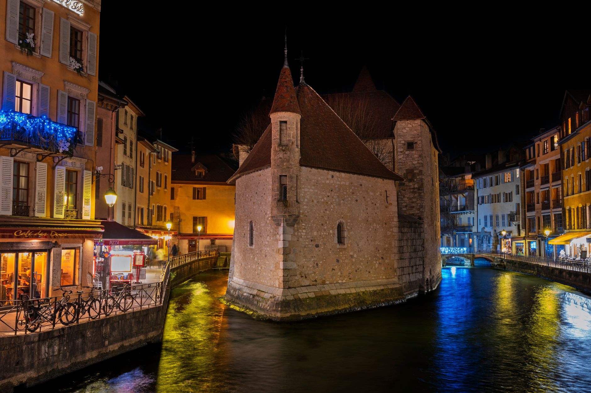 Pont des Amours, kovový most přes kanál v Annecy s jezerem a horami v pozadí