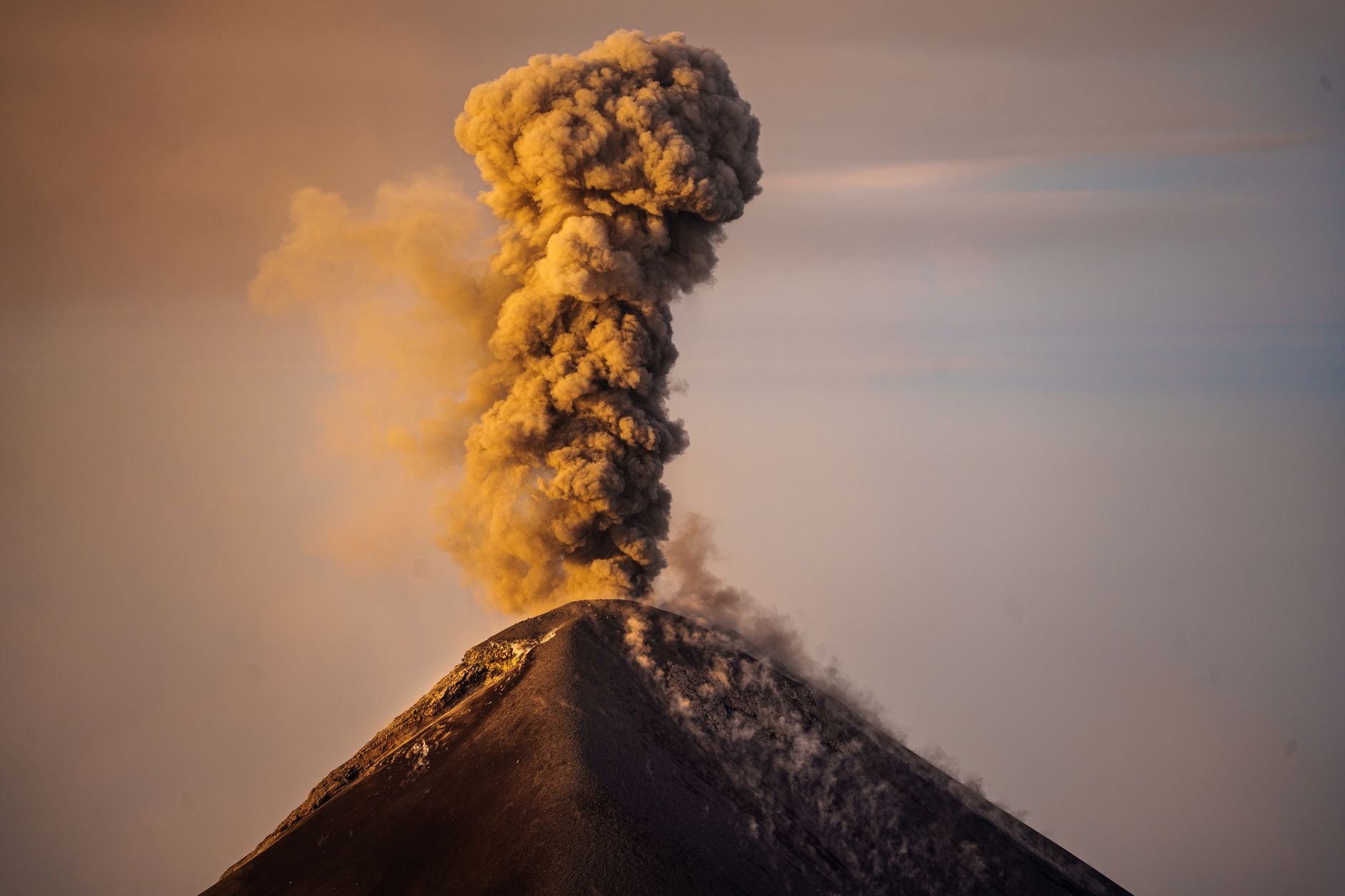 Činná sopka Fuego v Guatemale chrlící popel s kouřovým oblakem za soumraku