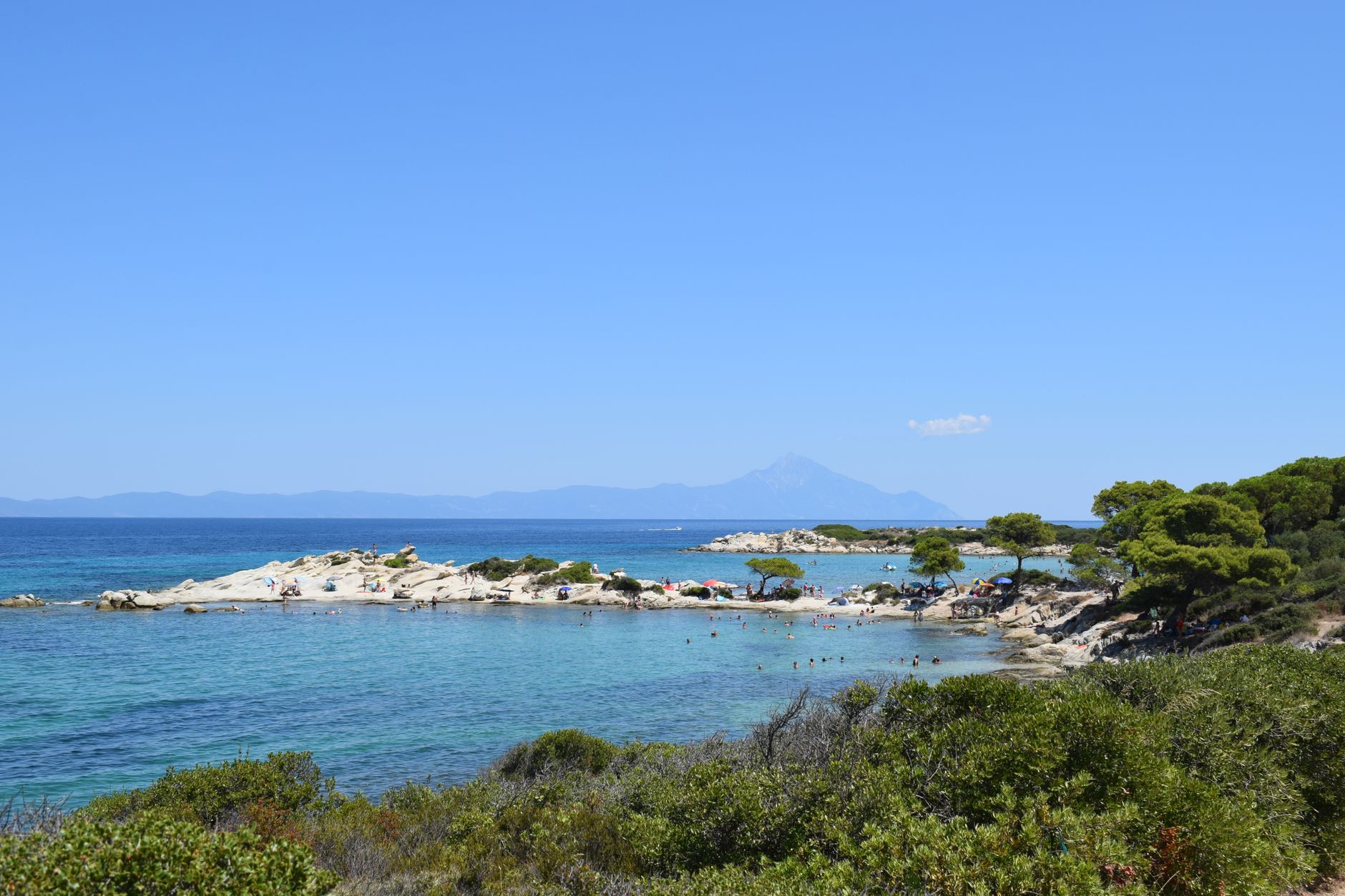 Klikatá pobřežní cesta lemovaná borovicemi nad tyrkysovým mořem na poloostrově Chalkidiki