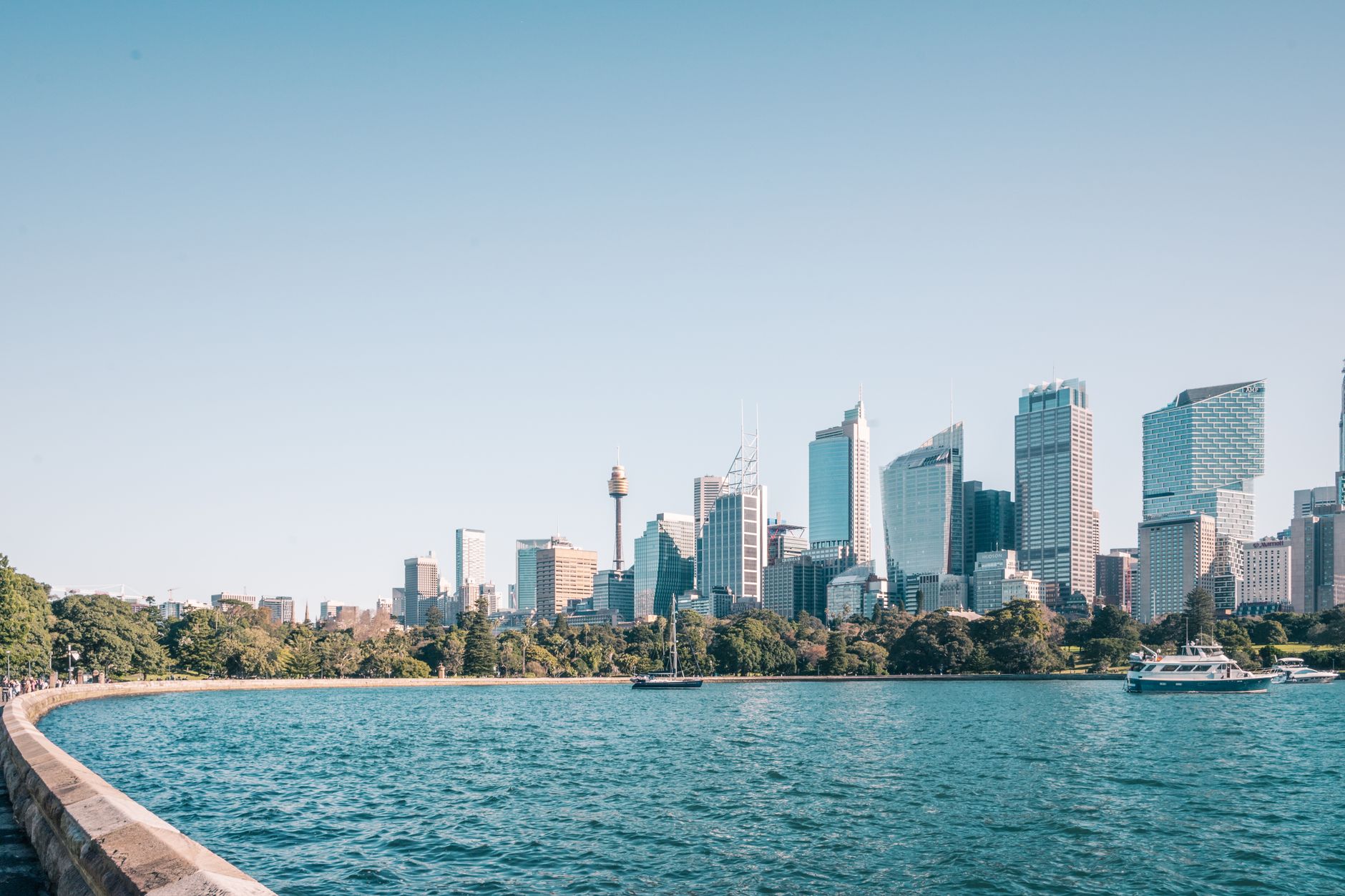 Panorama přístavu v Sydney s mrakodrapy centra a trajekty na vodě za soumraku