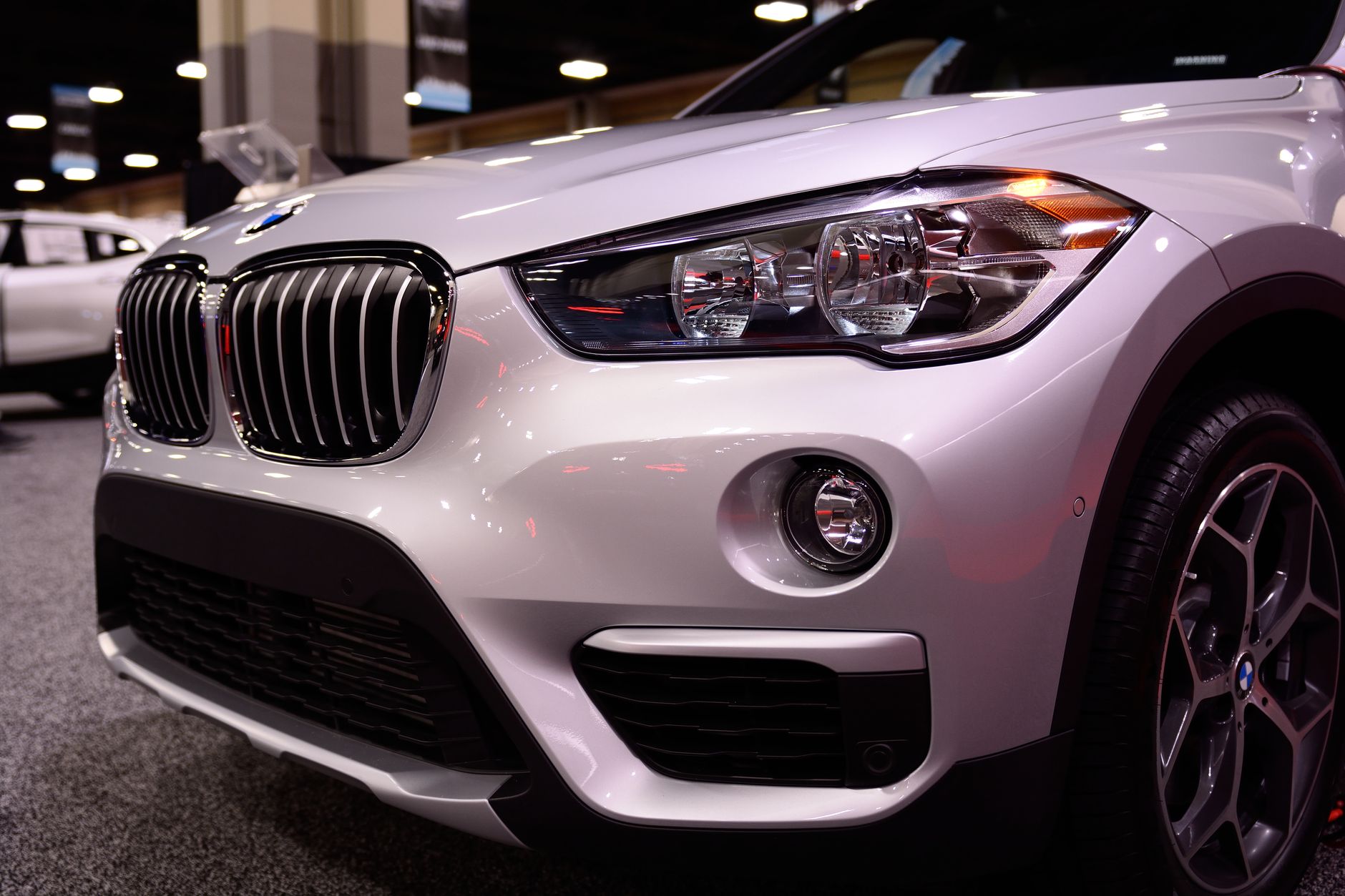 Detail předního masky a loga sportovního vozu na výstavním stánku autosalonu
