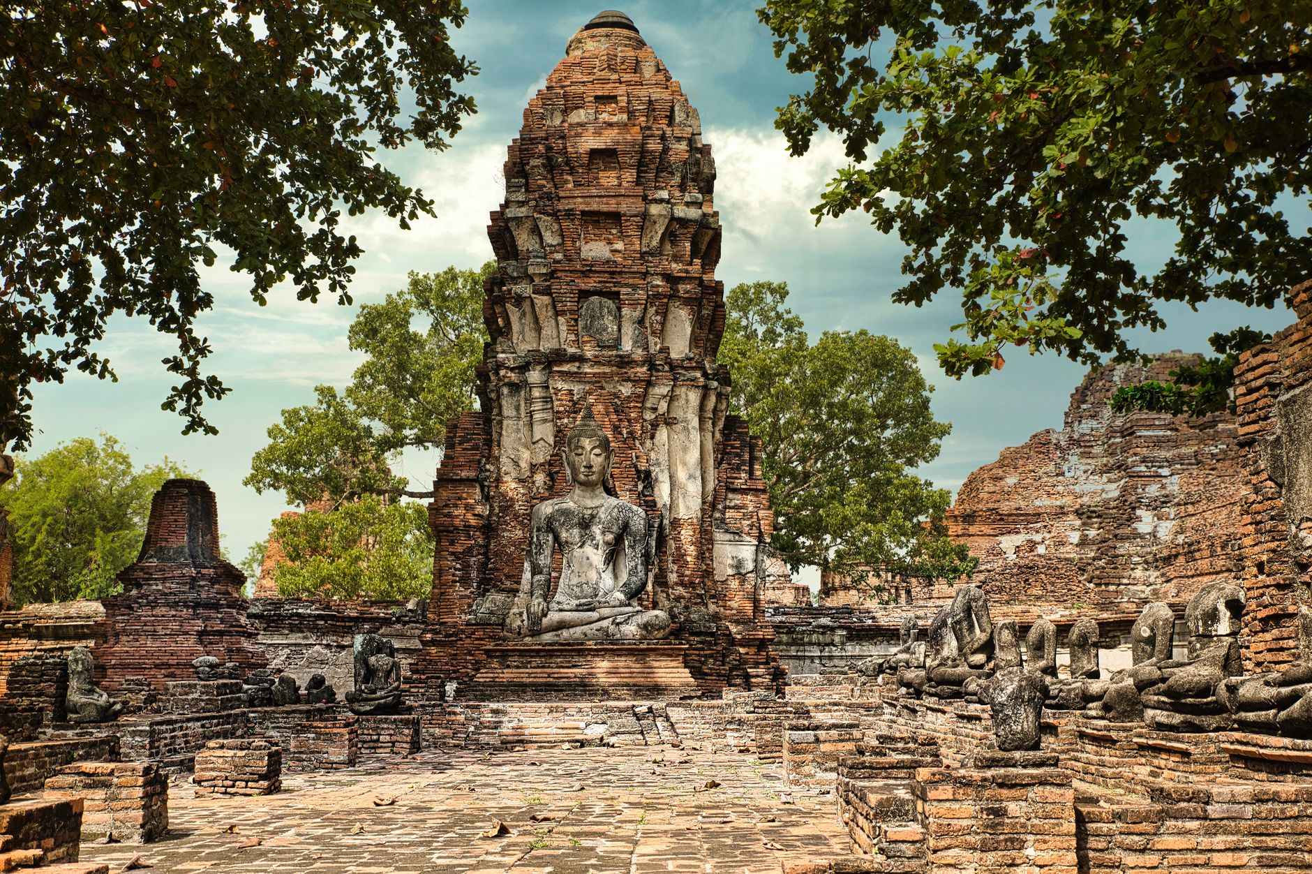 Cihlové ruiny chrámu Wat Mahathat v Ayutthaji s řadou prang věží za soumraku