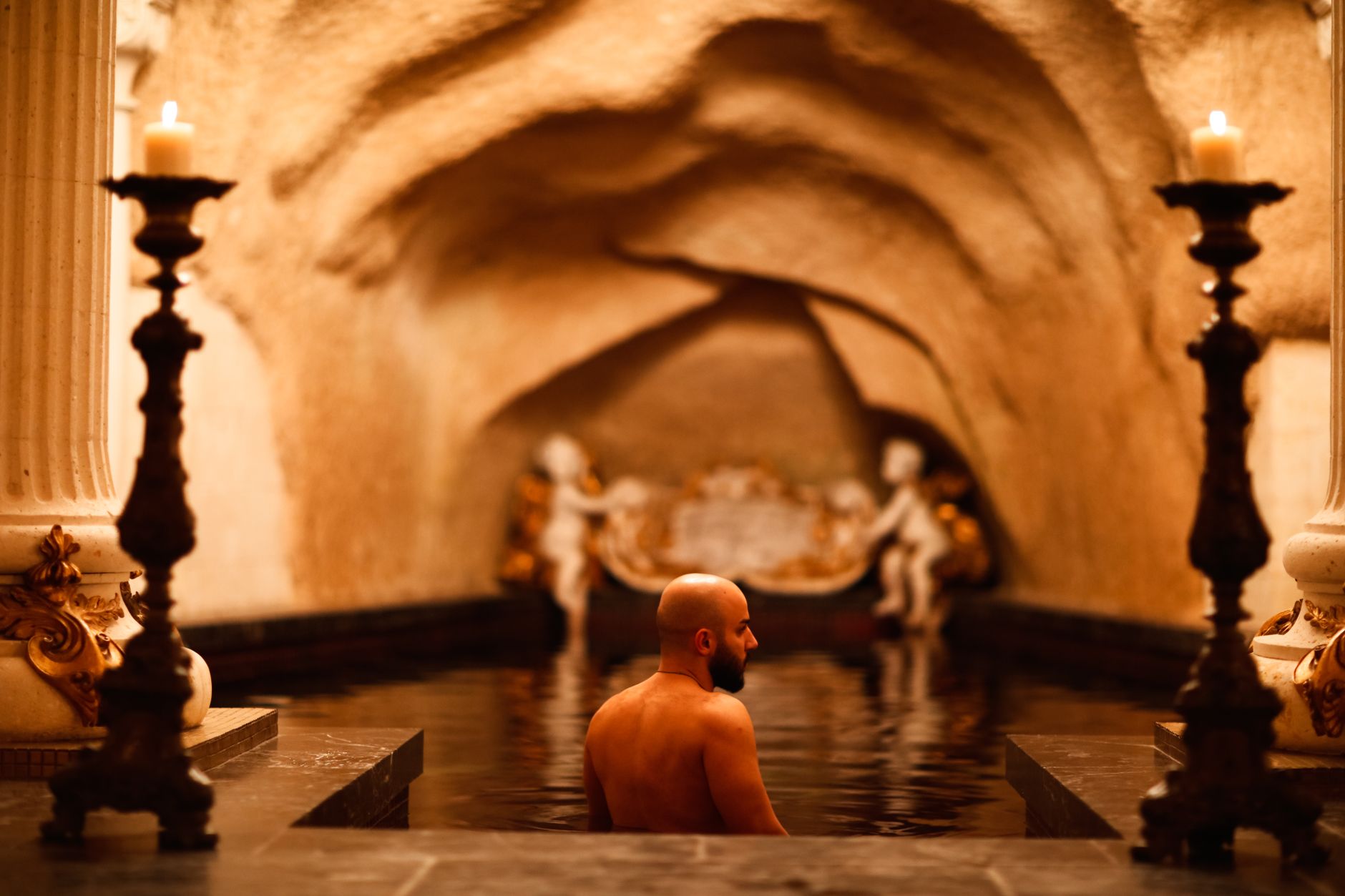 Termální bazén v lázních Baden-Badenu s párou stoupající nad vodou a kamennými oblouky