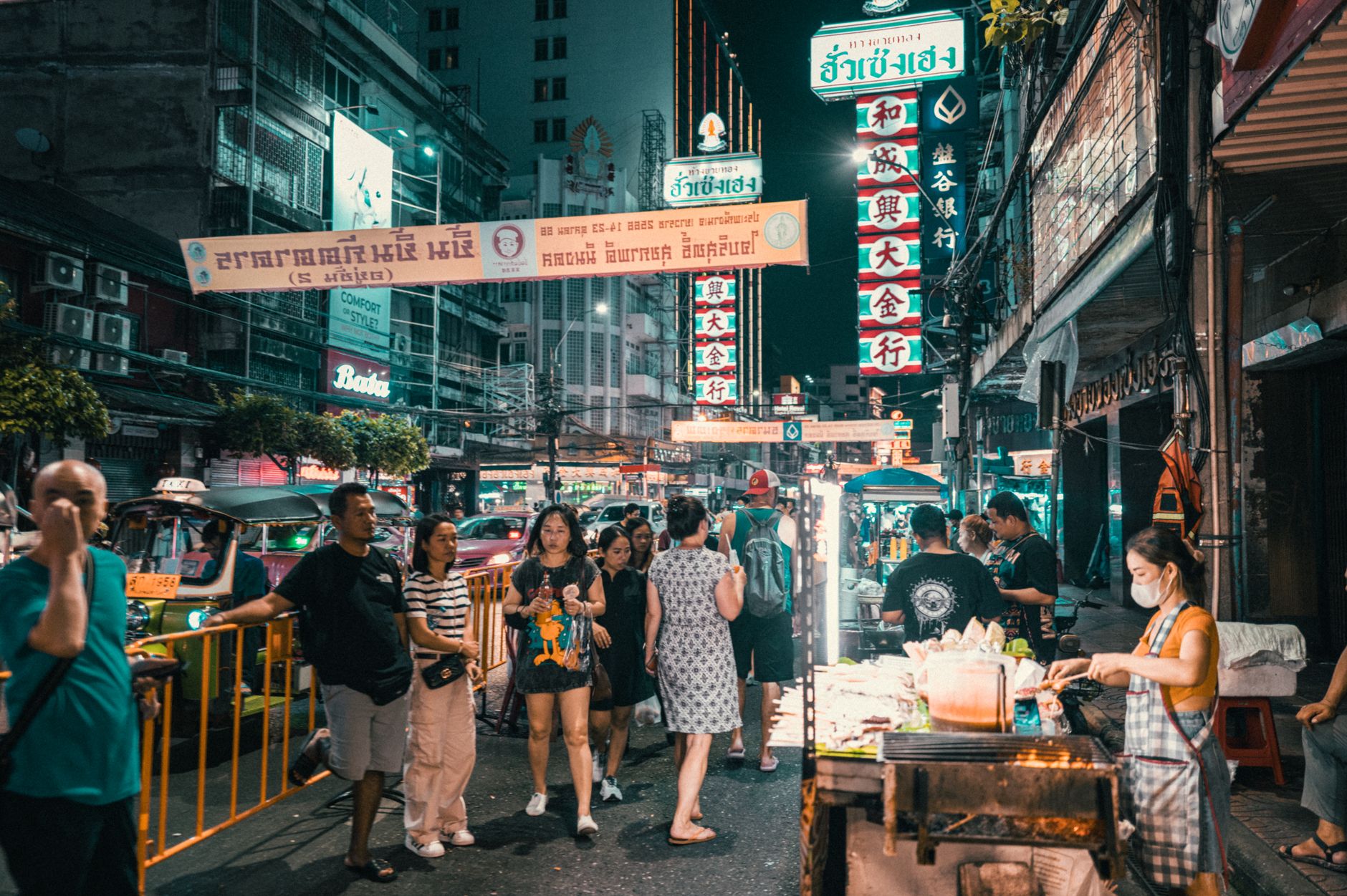 Stánky se street foodem ve čtvrti Chinatown Yaowarat v Bangkoku večer s neonovými nápisy