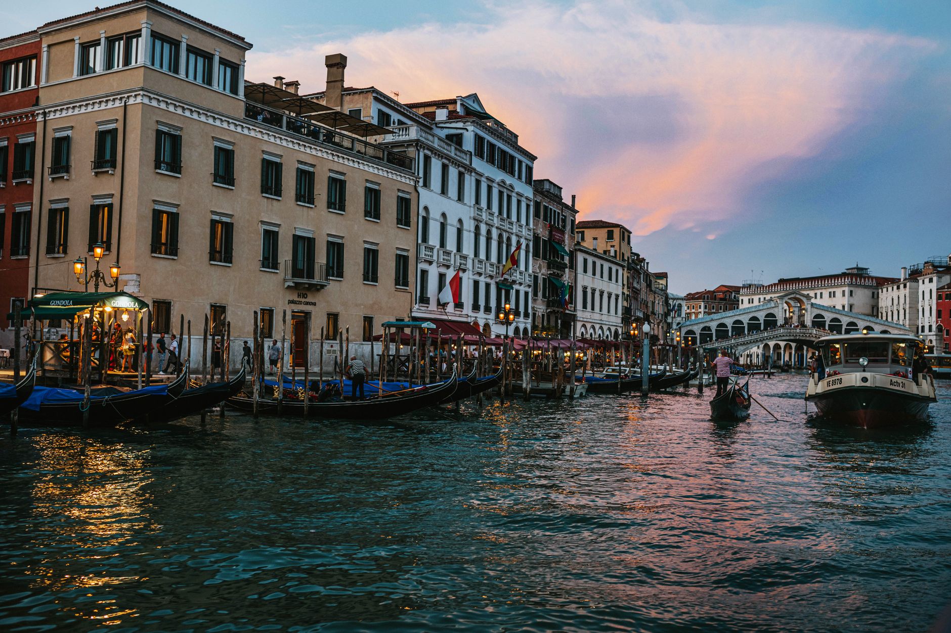 Most Rialto přes Canal Grande v Benátkách s obchody a projíždějícími loďmi