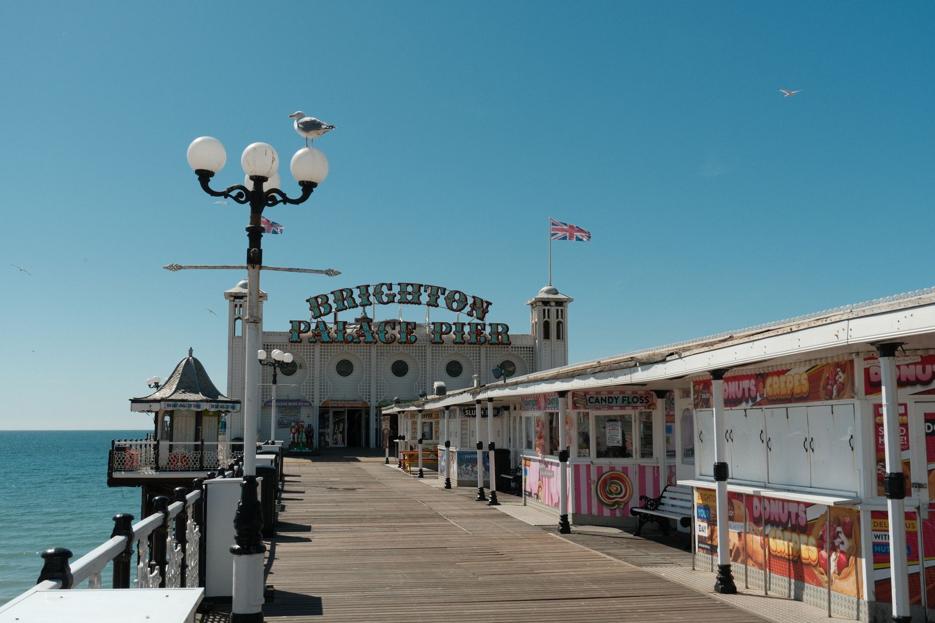 Brighton Palace Pier nad mořem v Brightonu s molem, kolotoči a oblázkovou pláží