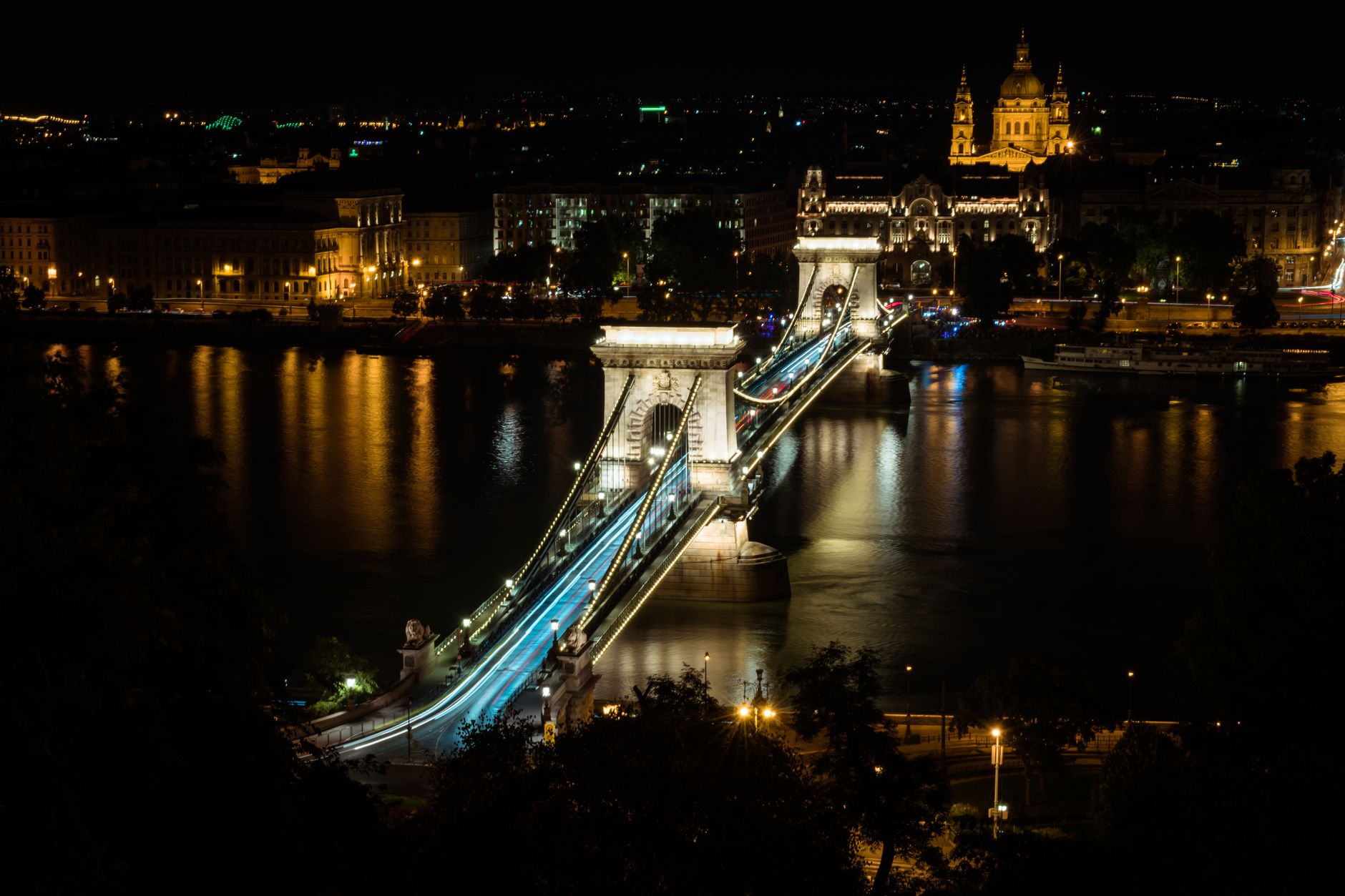 Řetězový most přes Dunaj v Budapešti večer s nasvícenými kamennými lvy a Budínským hradem