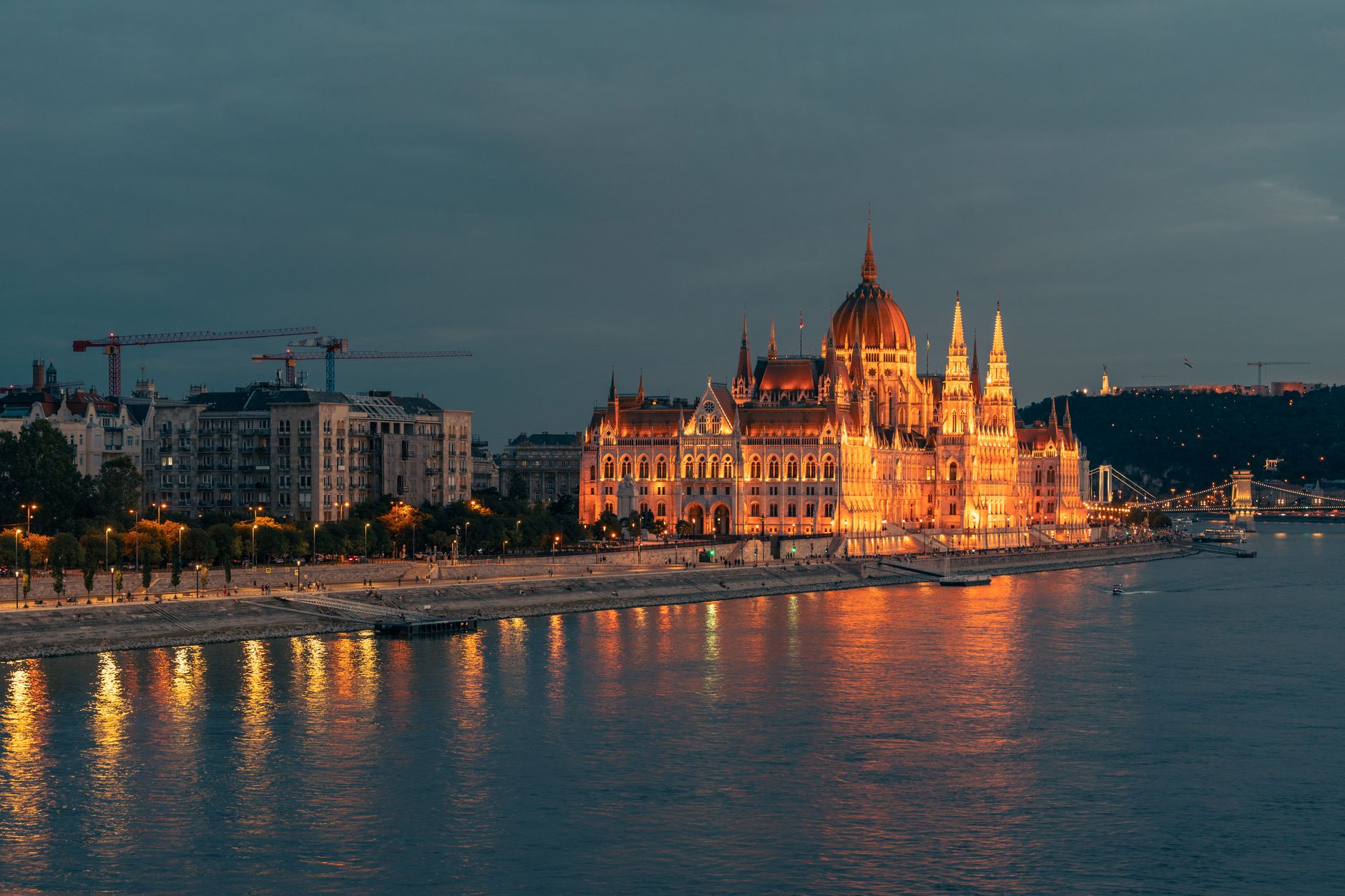 Maďarský parlament na břehu Dunaje v Budapešti za soumraku s rozsvícenou fasádou