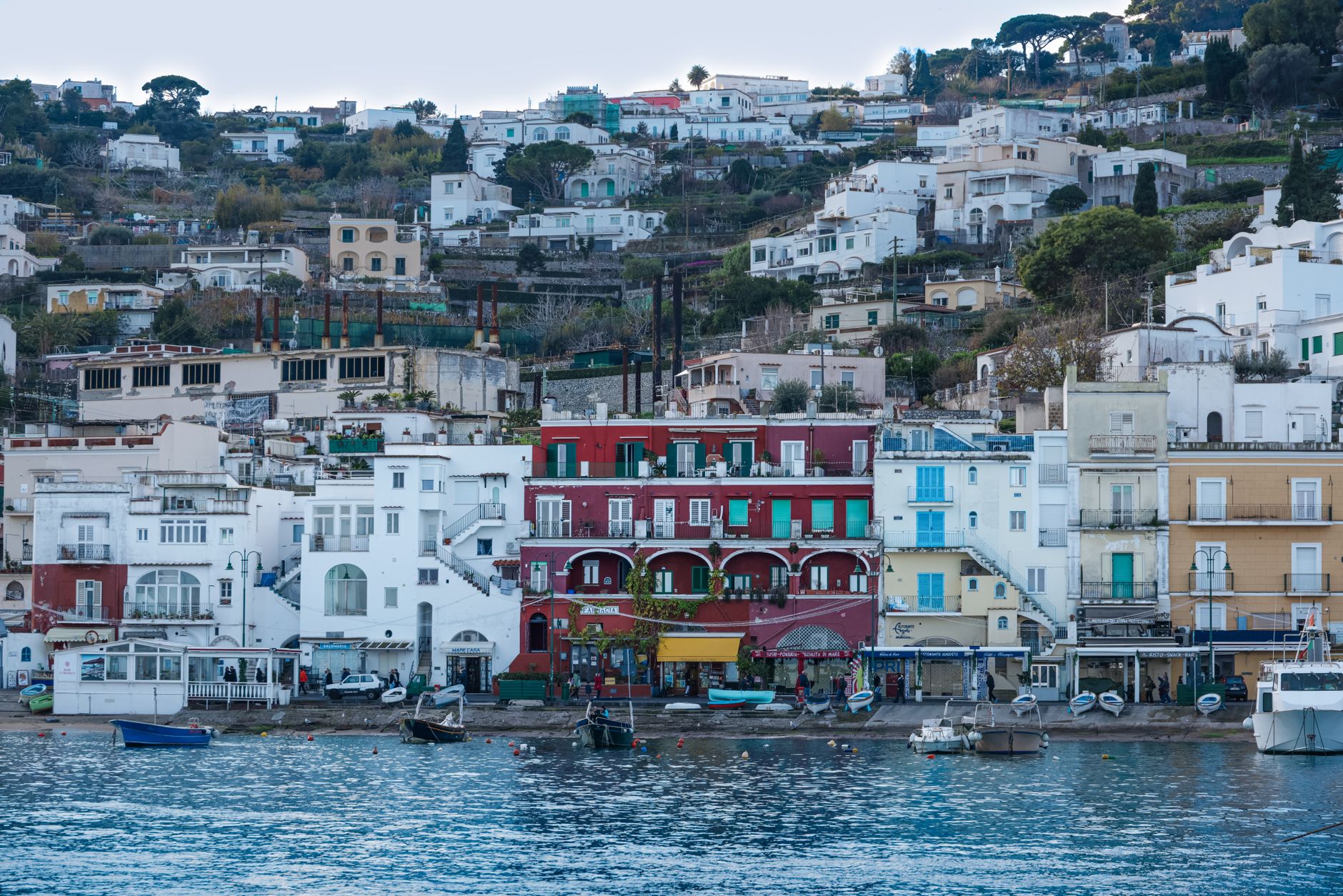 Pohled na přístav Marina Grande na Capri s barevnými domky a lodičkami u tyrkysové vody