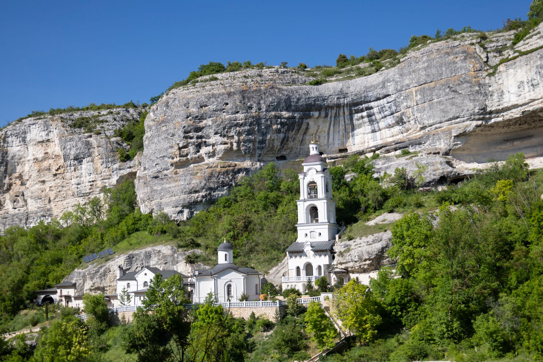 Klášter Ostrog zabudovaný do svislé bílé skály nad zelenými svahy v Černé Hoře