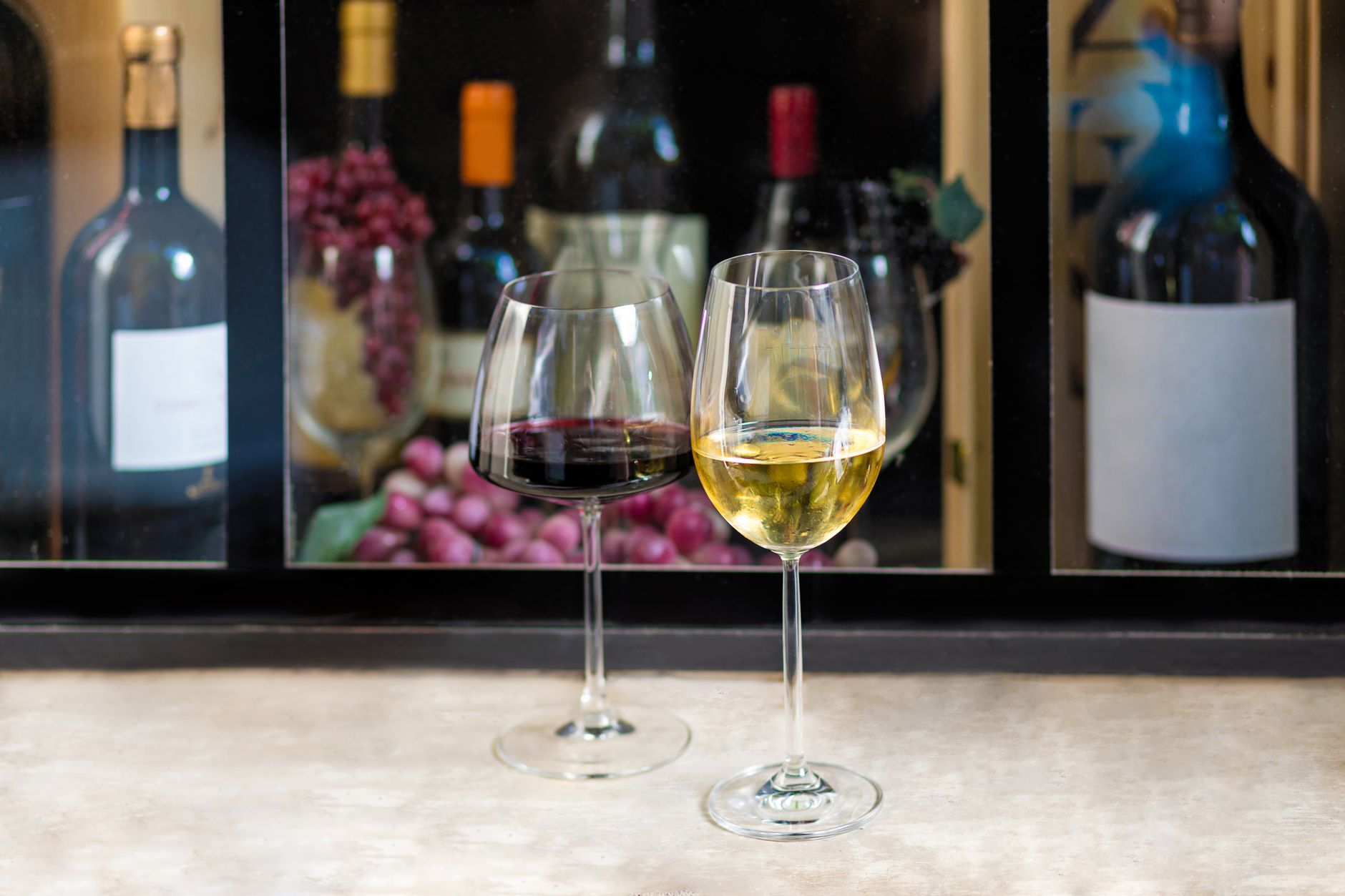 Dvě sklenice šampaňského a lahev na stole s vinicemi v pozadí