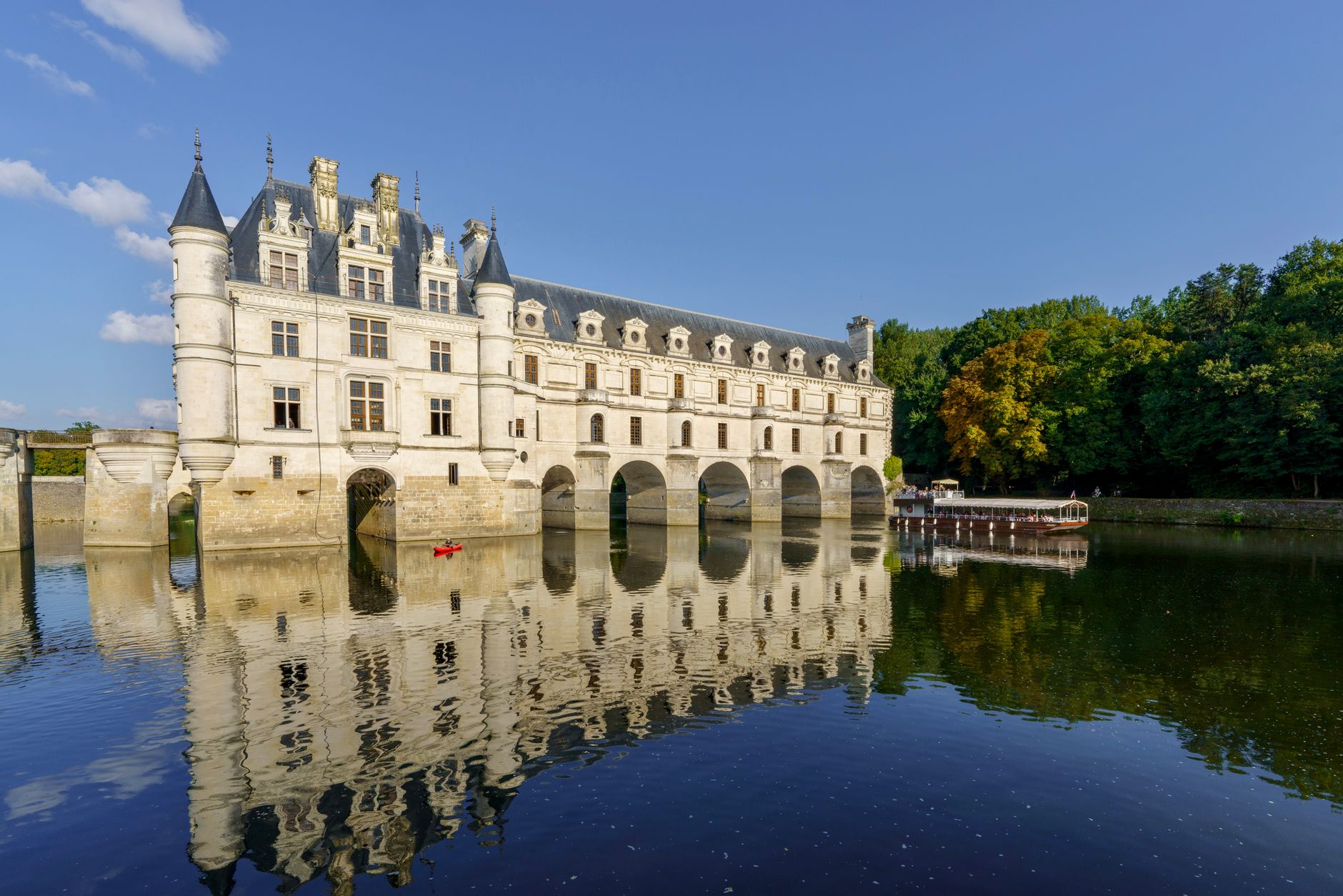 Renesanční zámek Chenonceau s galerií klenoucí se přes řeku Cher obklopený zelení