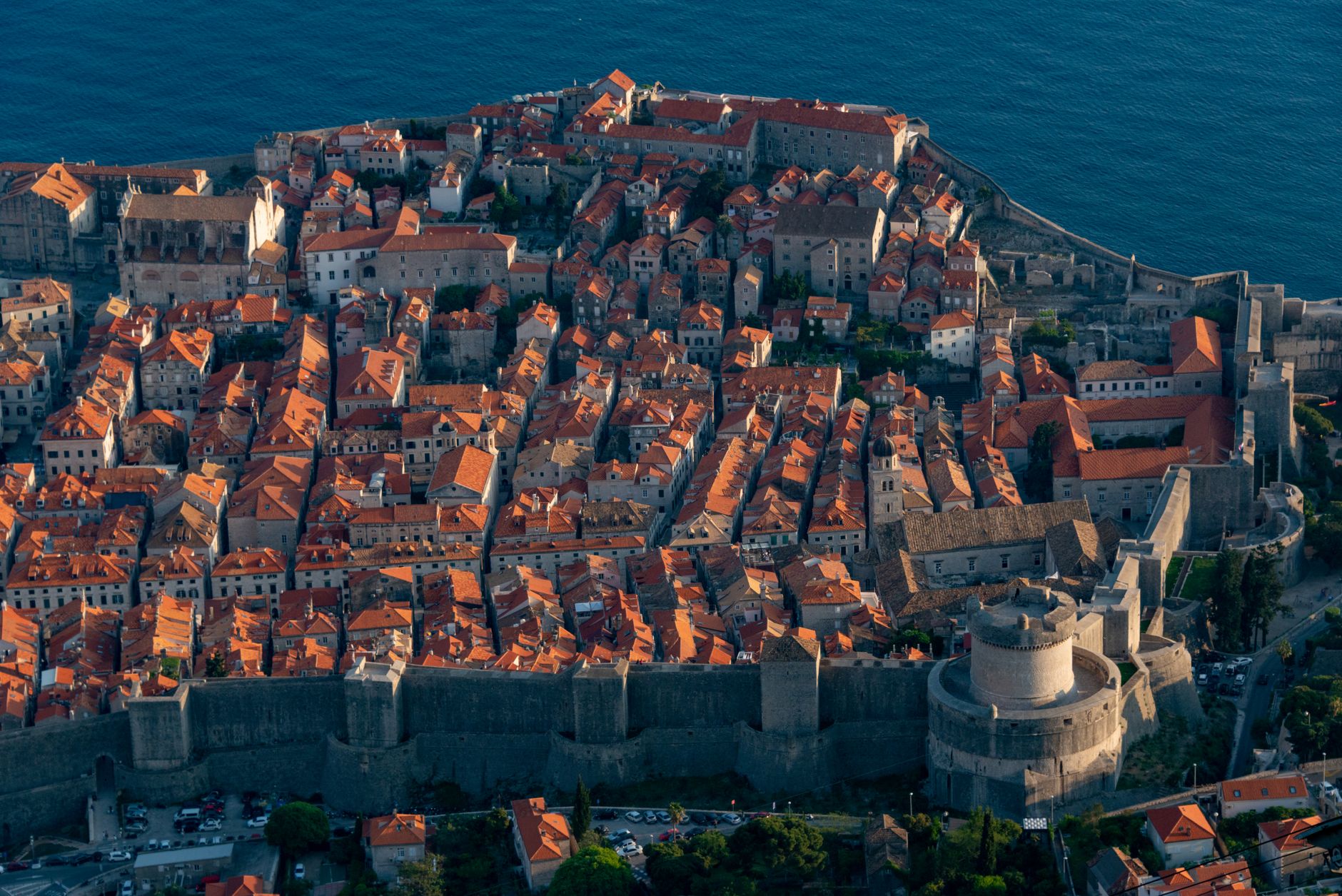 Pohled na staré město Dubrovník s hradbami a oranžovými střechami nad modrým Jaderským mořem