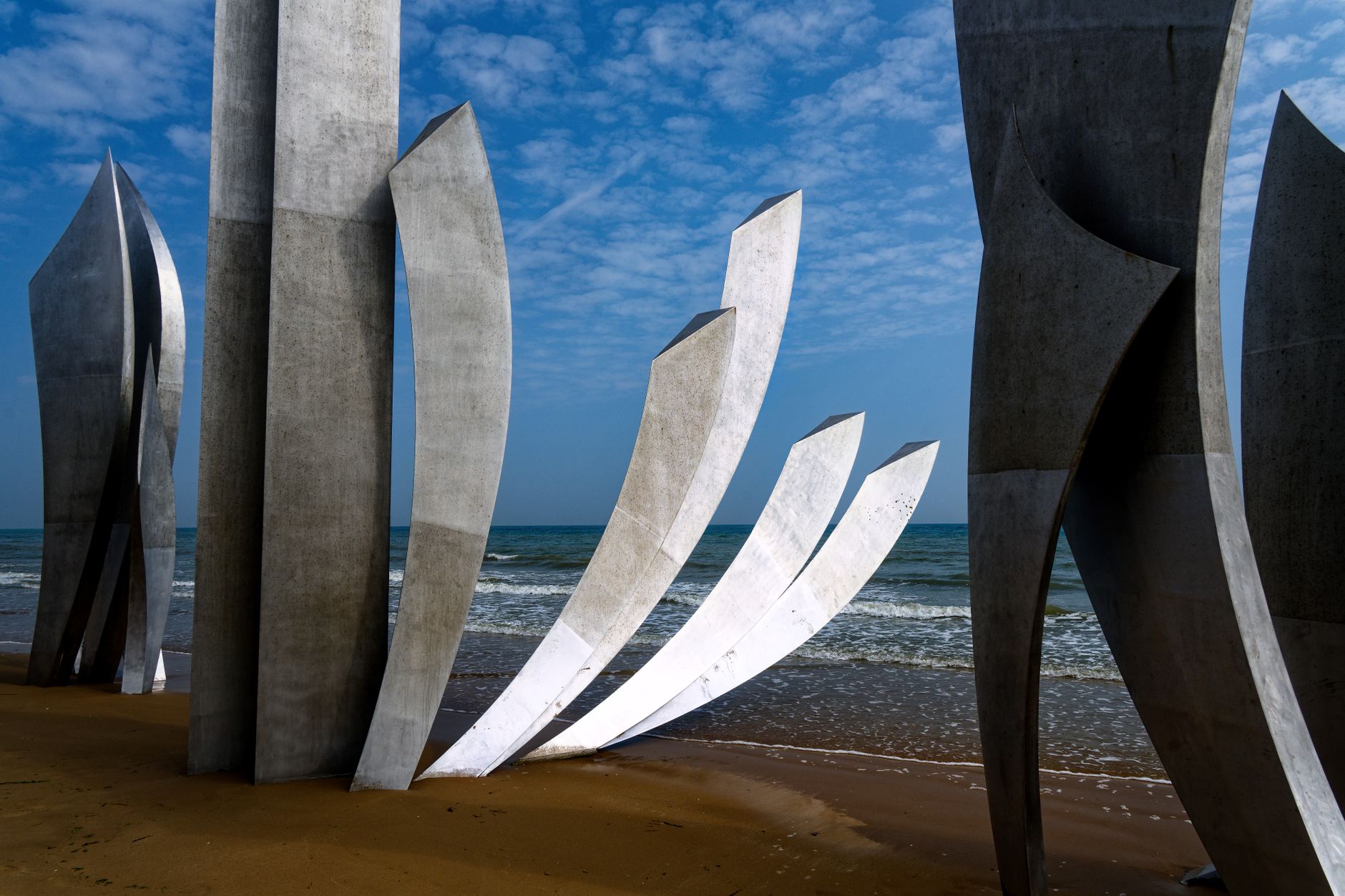 Pohled na pláž Omaha Beach v Colleville-sur-Mer v Normandii s rozlehlou písčinou a klidným mořem