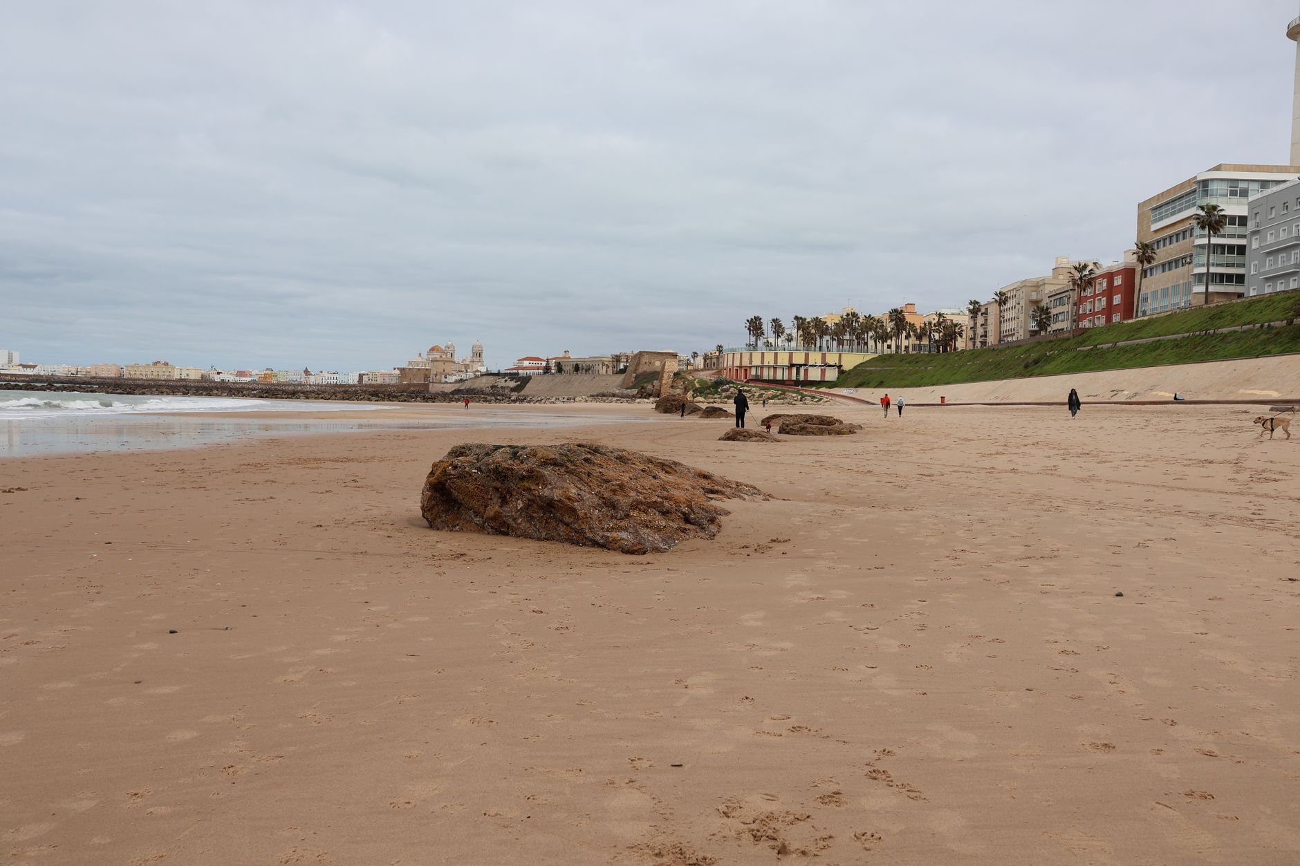 Zlatá písečná pláž na Costa Dorada s mělkým tyrkysovým mořem a palmami podél promenády