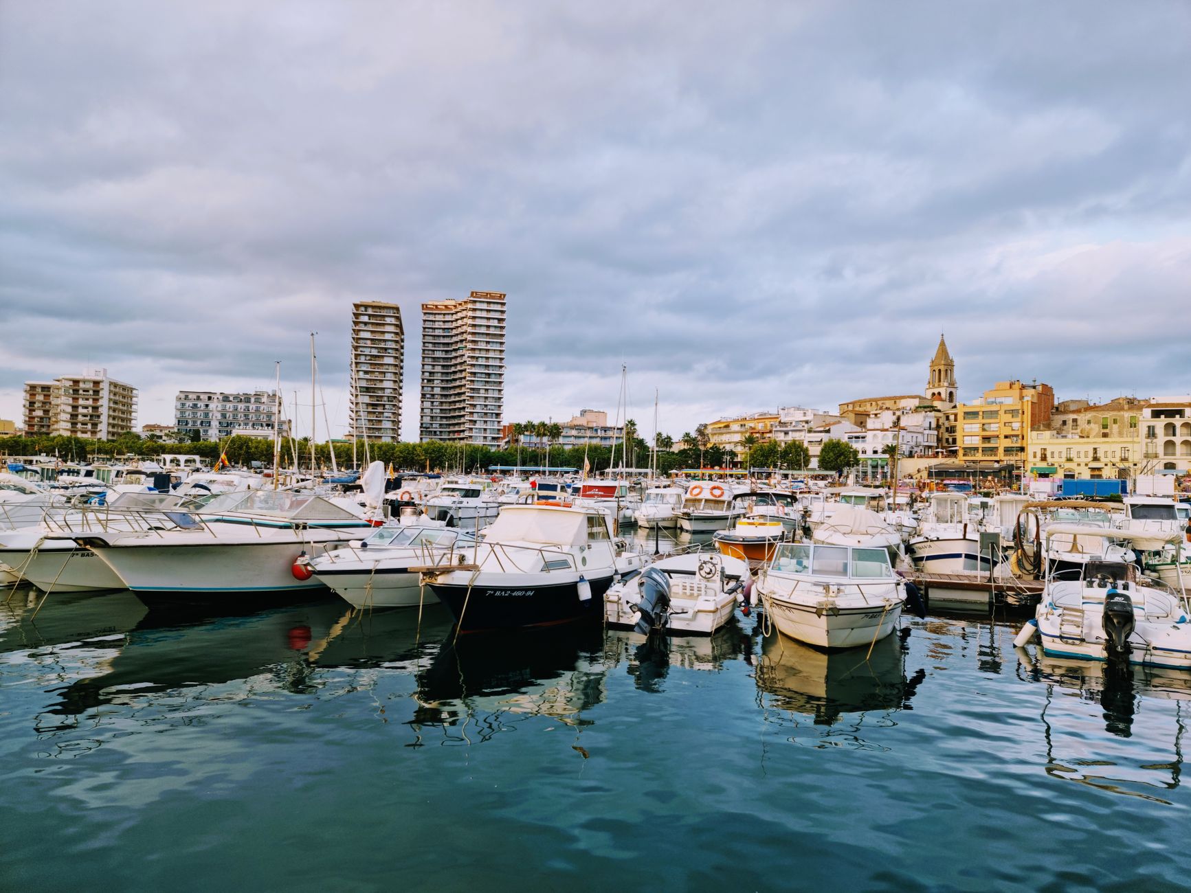 Klidné přístavní městečko Cambrils s rybářskými loděmi a majákem na Costa Dorada