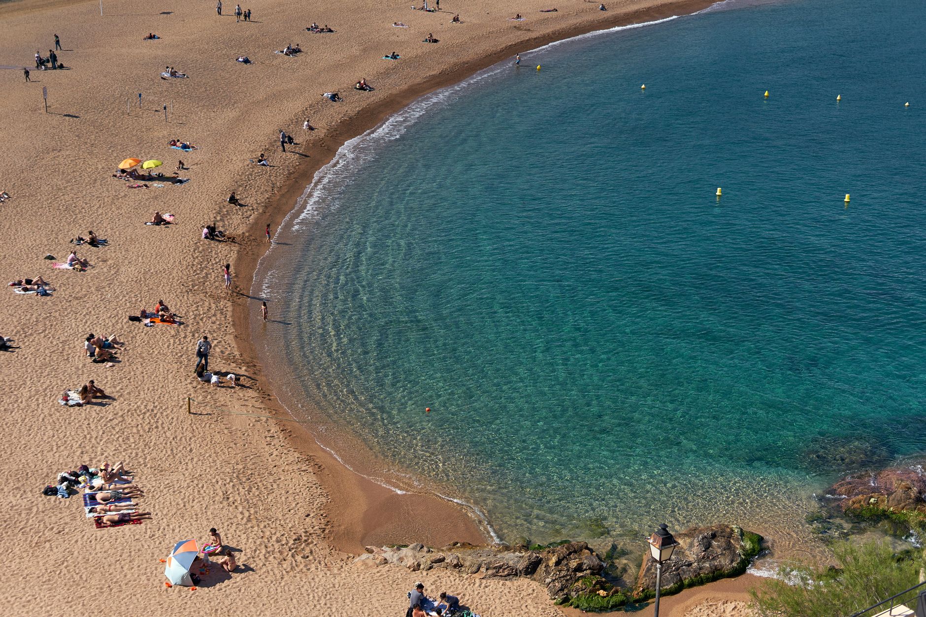 Dlouhá písečná pláž Costa Dorada se zlatým pískem a tyrkysovým mořem za soumraku