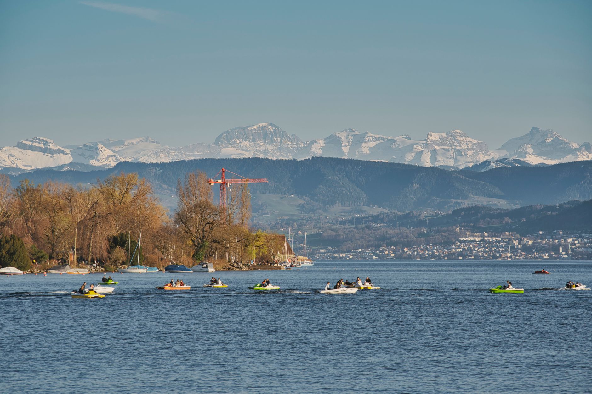 Curychské jezero s loděmi a zasněženými alpskými štíty v pozadí