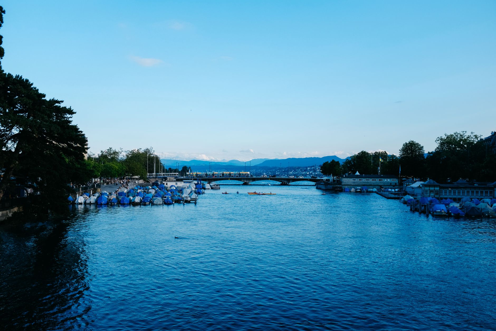 Panorama Curychu s řekou Limmat, kostelními věžemi a Alpami v pozadí