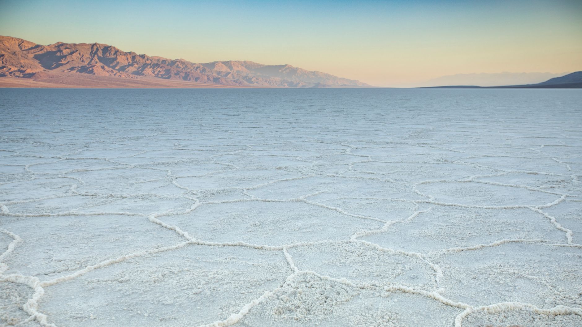 Vyprahlé solné pláně Badwater Basin v národním parku Death Valley s hřebenem hor v pozadí