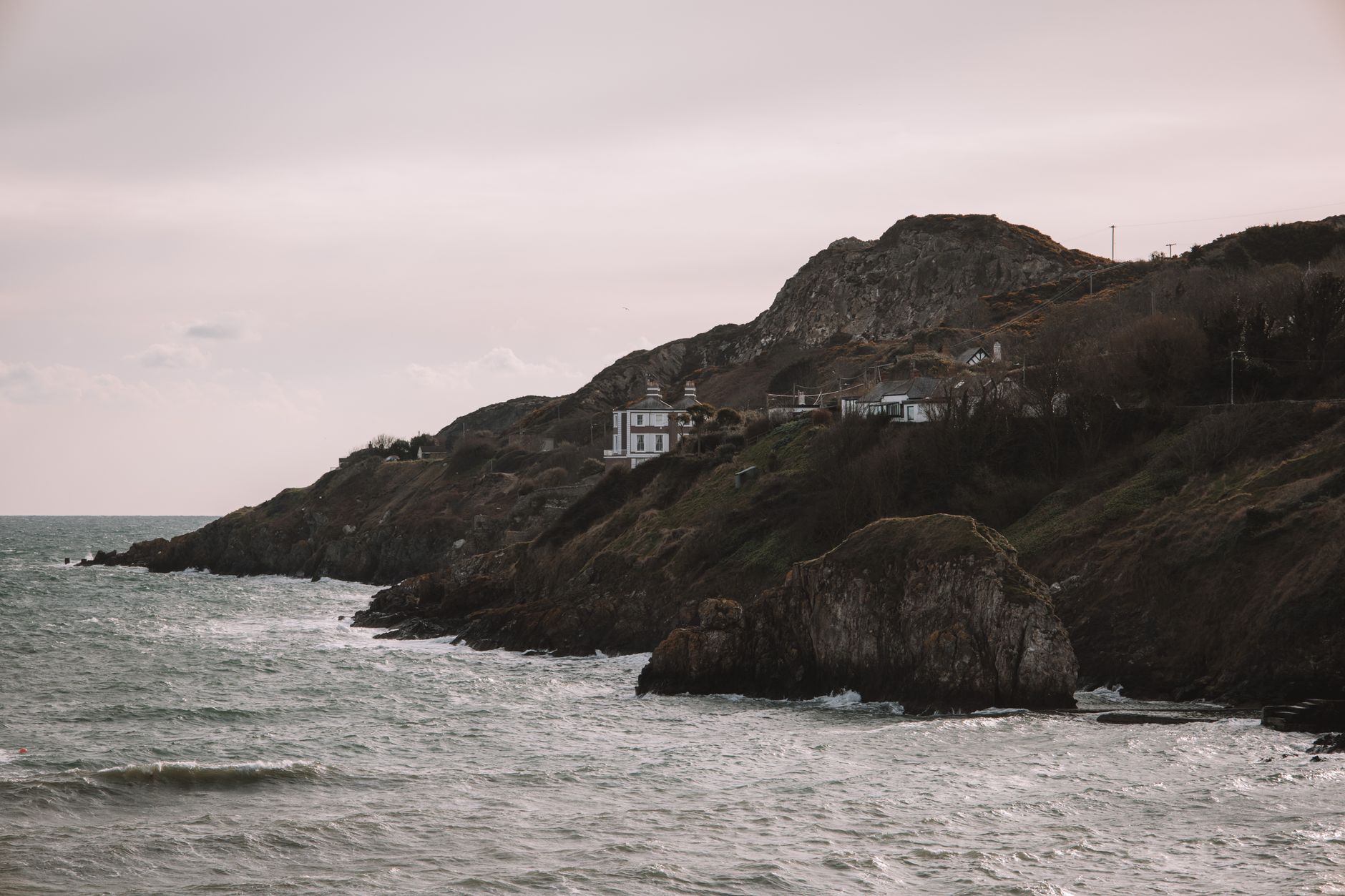 Skalnaté útesy poloostrova Howth u Dublinu s travnatou stezkou a výhledem na Irské moře