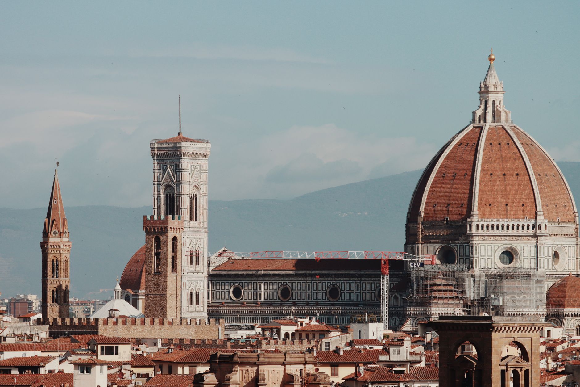 Katedrála Santa Maria del Fiore s cihlovou kupolí a zvonicí Giotta nad střechami Florencie