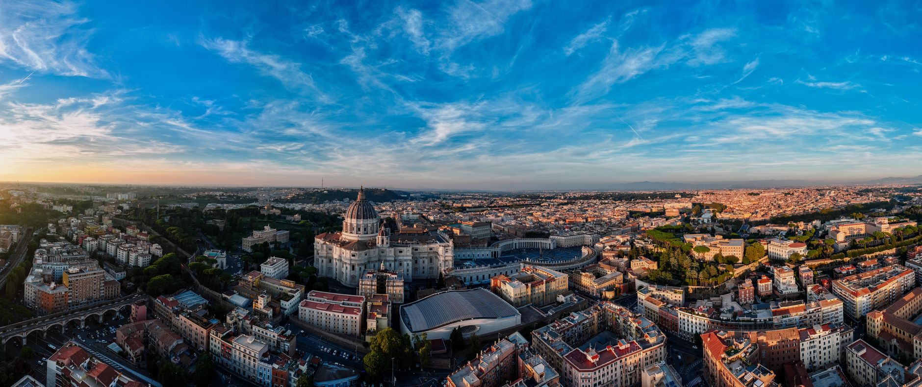 Panoramatický pohled na Řím s kupolí baziliky svatého Petra nad střechami města za soumraku