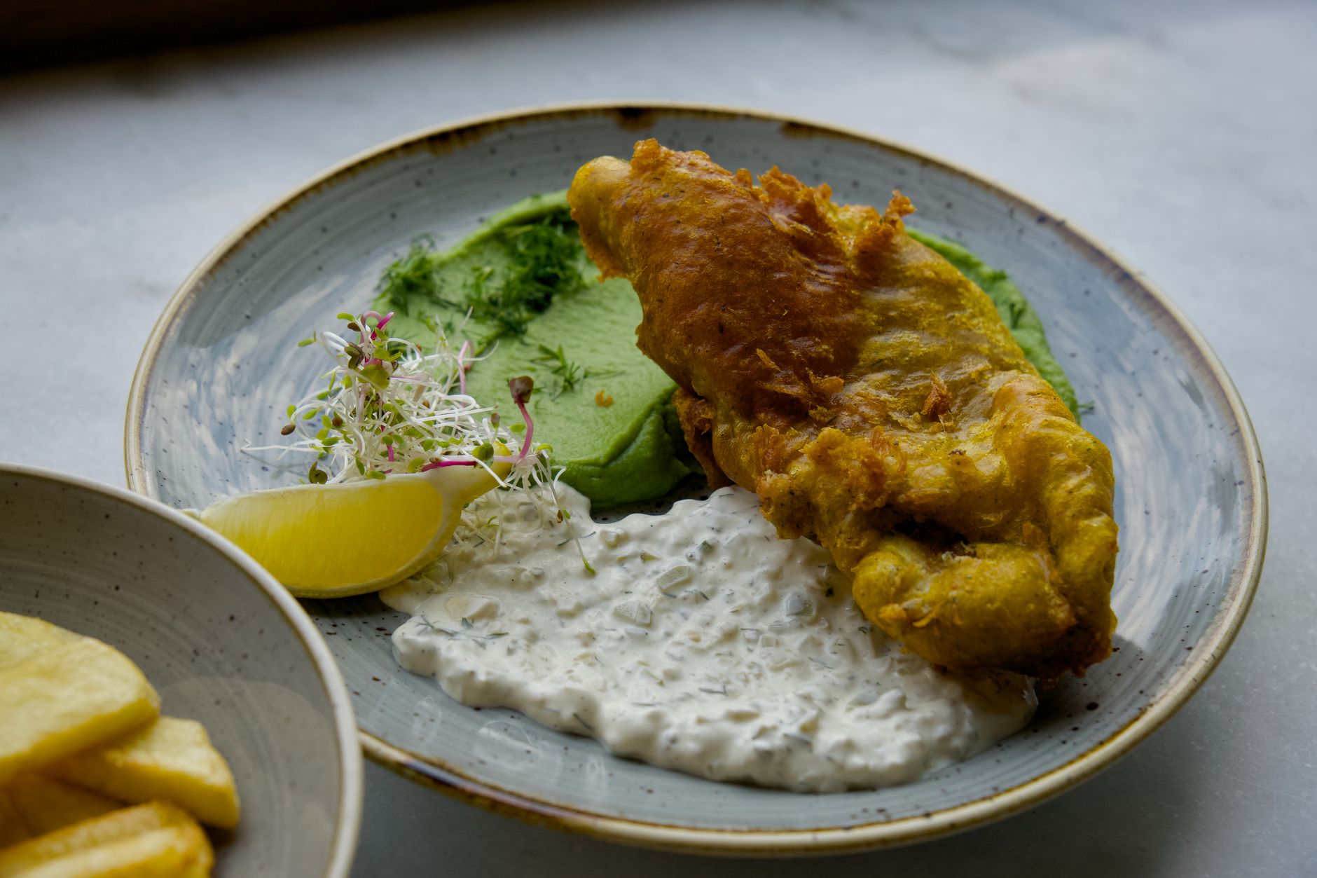 Tradiční anglické fish and chips na talíři s hráškem v pubu