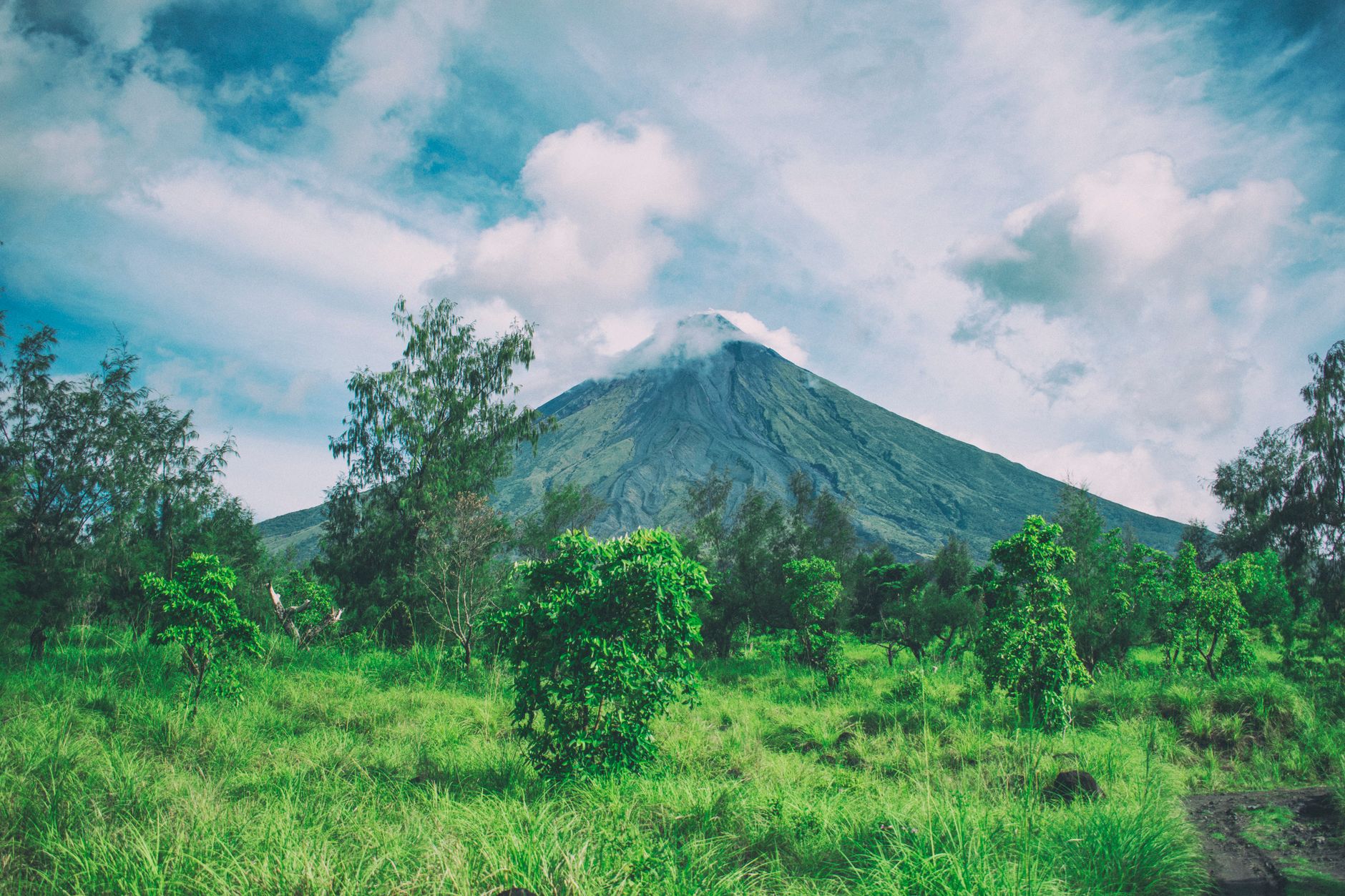 Souměrný kužel činné sopky Mayon nad zelenou krajinou u města Legazpi na ostrově Luzon