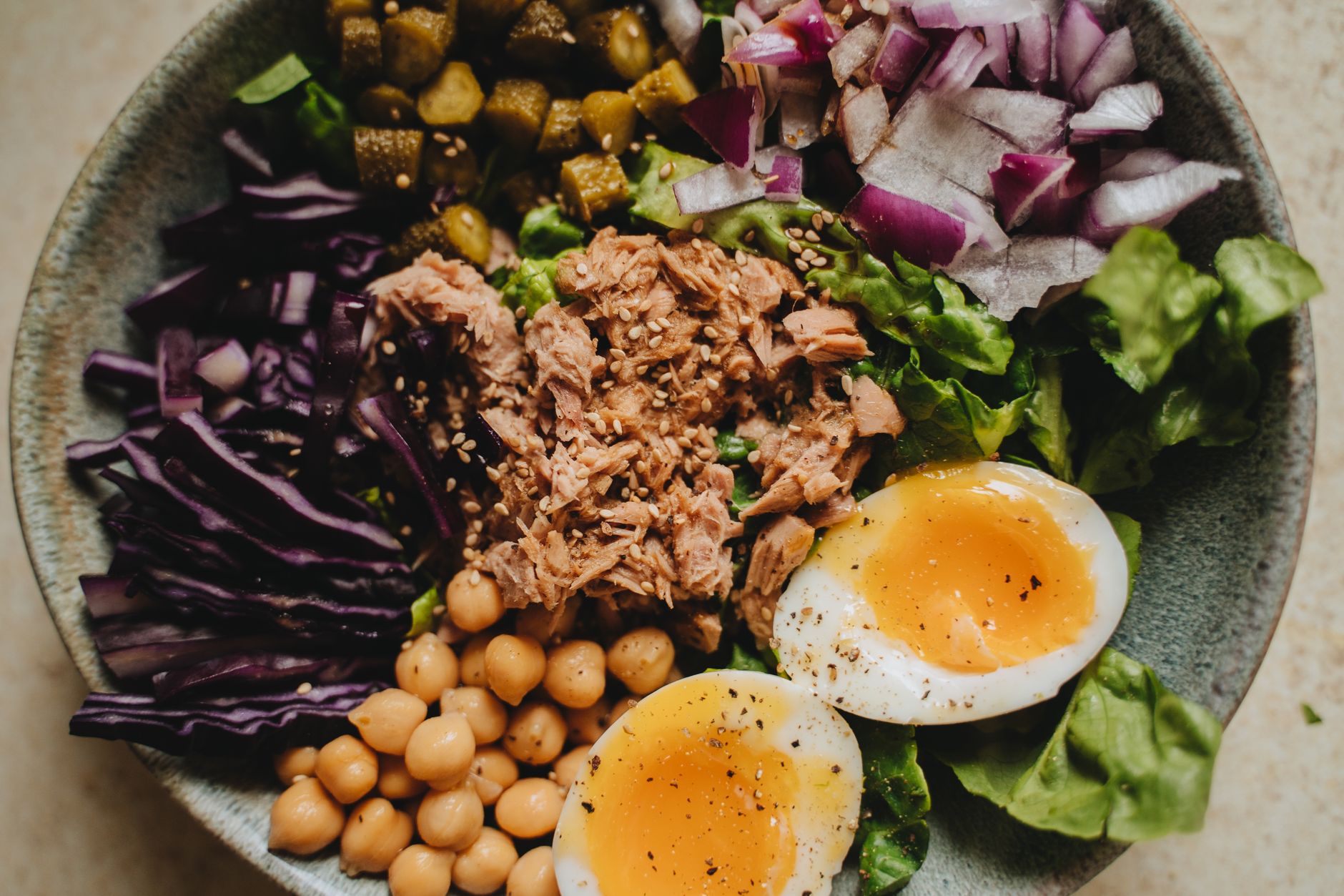 Talíř salade niçoise s rajčaty, vejci, olivami a tuňákem na stole v Nice