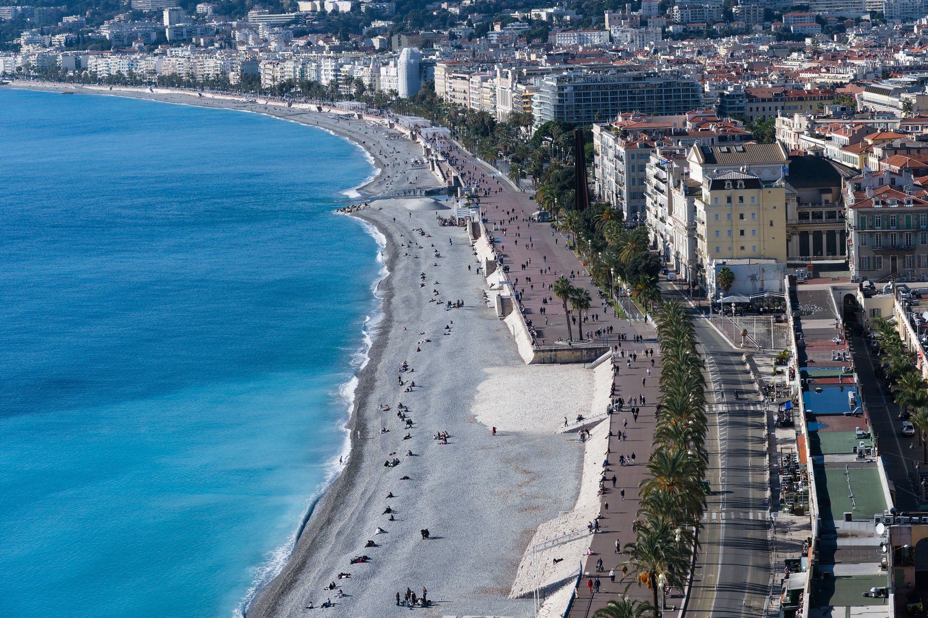 Pohled na záliv Baie des Anges a promenádu v Nice s tyrkysovým mořem a oranžovými střechami