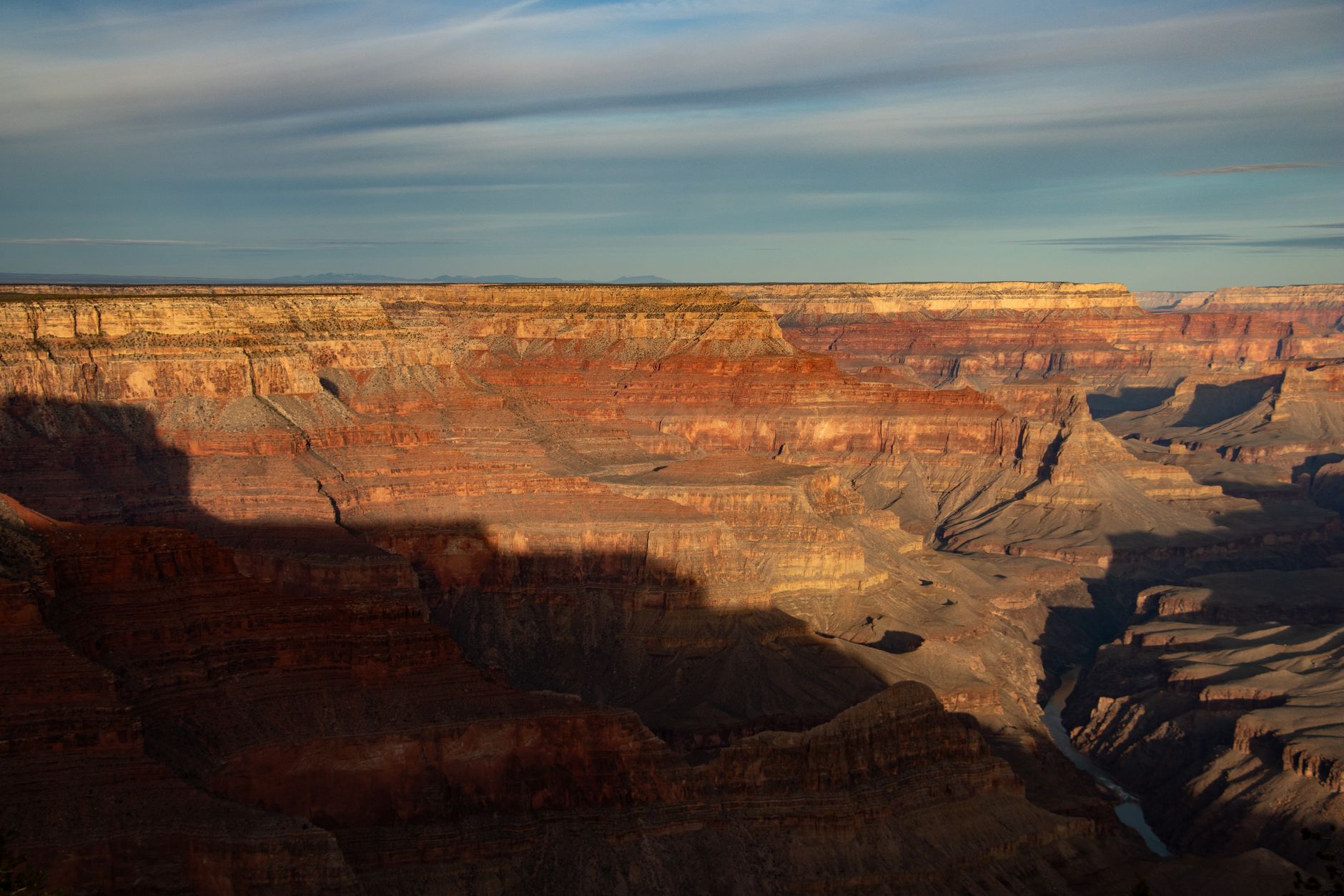 Zlaté světlo západu slunce dopadá na vrstevnaté skalní stěny Grand Canyonu
