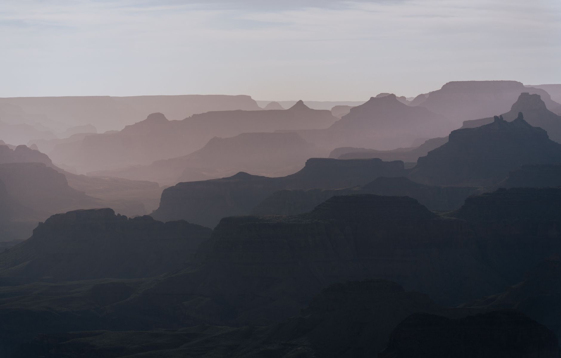 Panoramatický pohled na vrstevnaté skalní stěny Grand Canyonu při západu slunce z jižního okraje