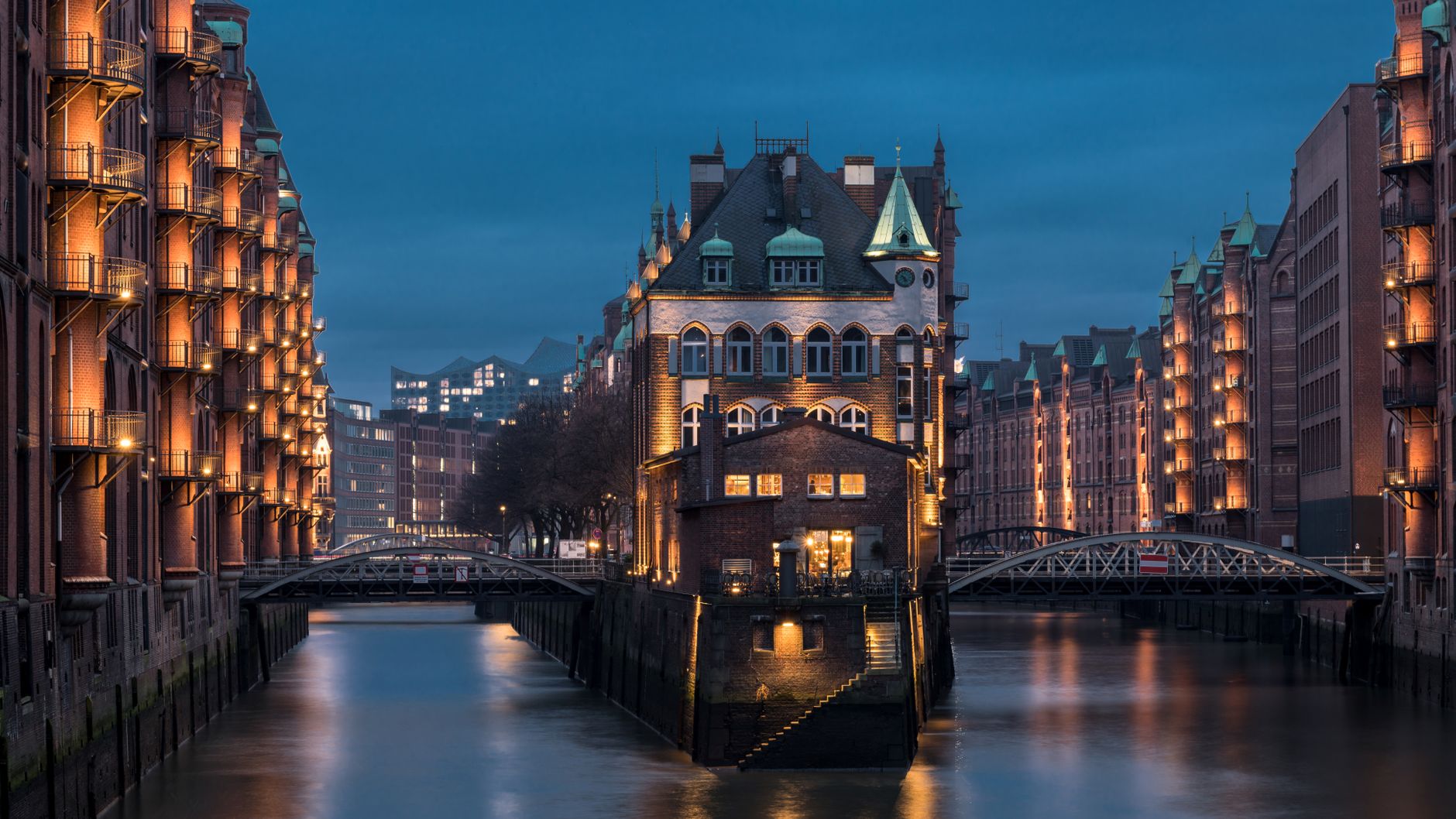 Cihlové skladiště Speicherstadt v Hamburku odrážející se ve vodním kanálu za soumraku