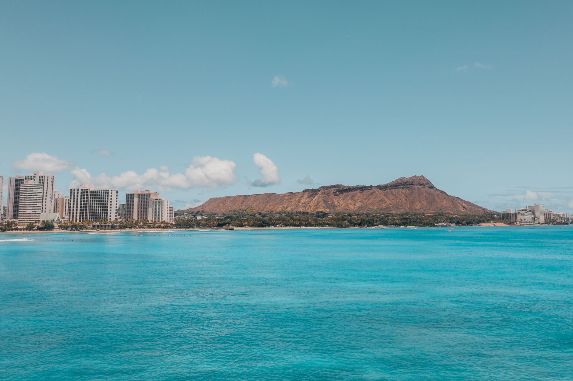 Pláž Waikiki v Honolulu s mrakodrapy a horou Diamond Head v pozadí