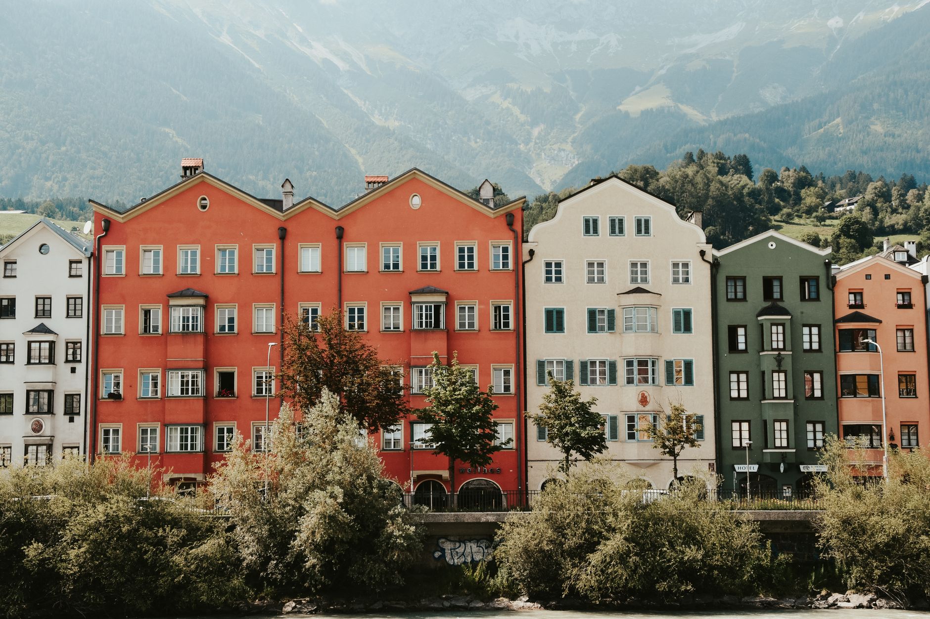 Panorama Innsbrucku s barevnými domy nad řekou Inn a zasněženými vrcholy Severního řetězce v pozadí