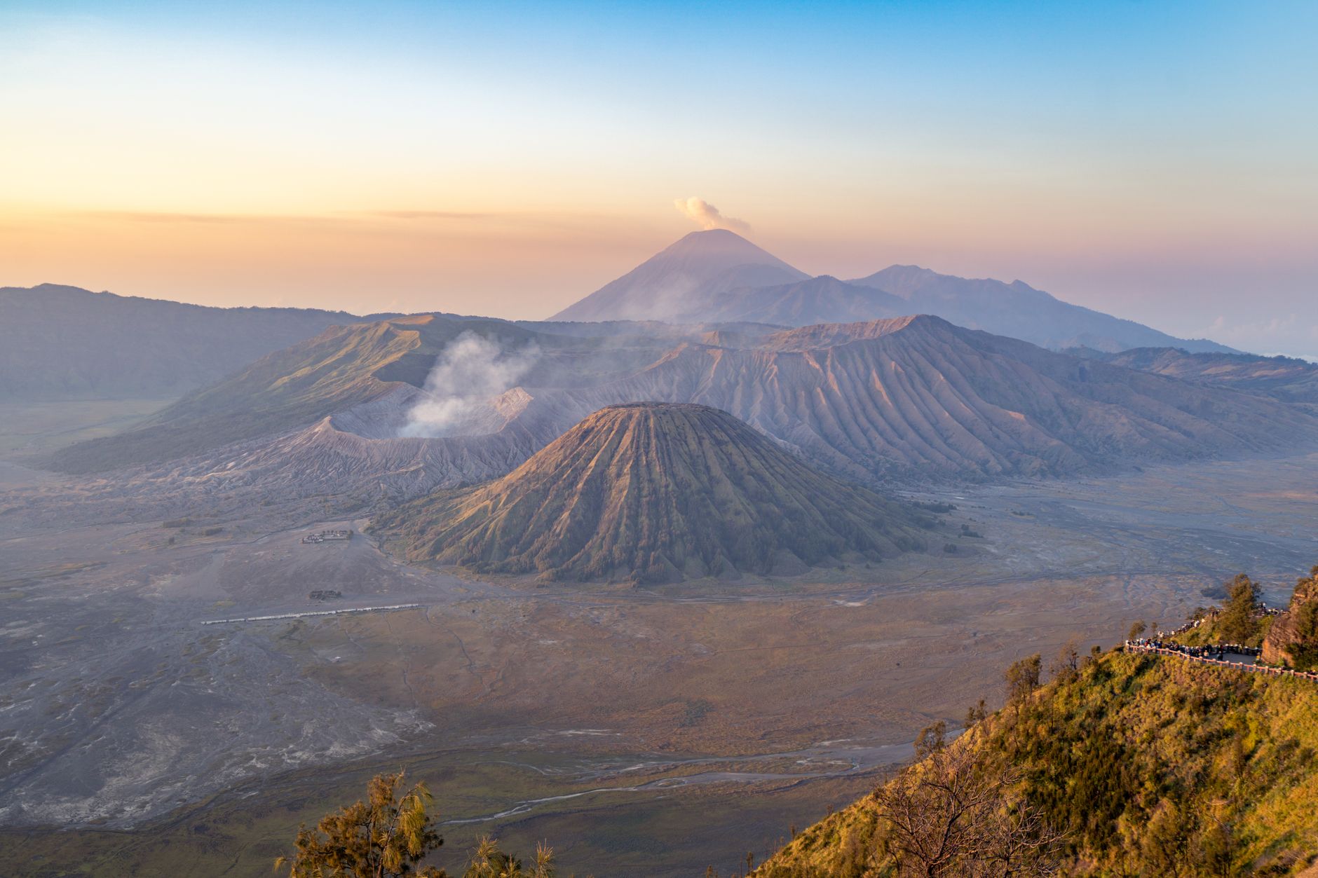 Kráter sopky Bromo na Jávě s kouřícím kuželem nad mořem sopečného popela za východu slunce