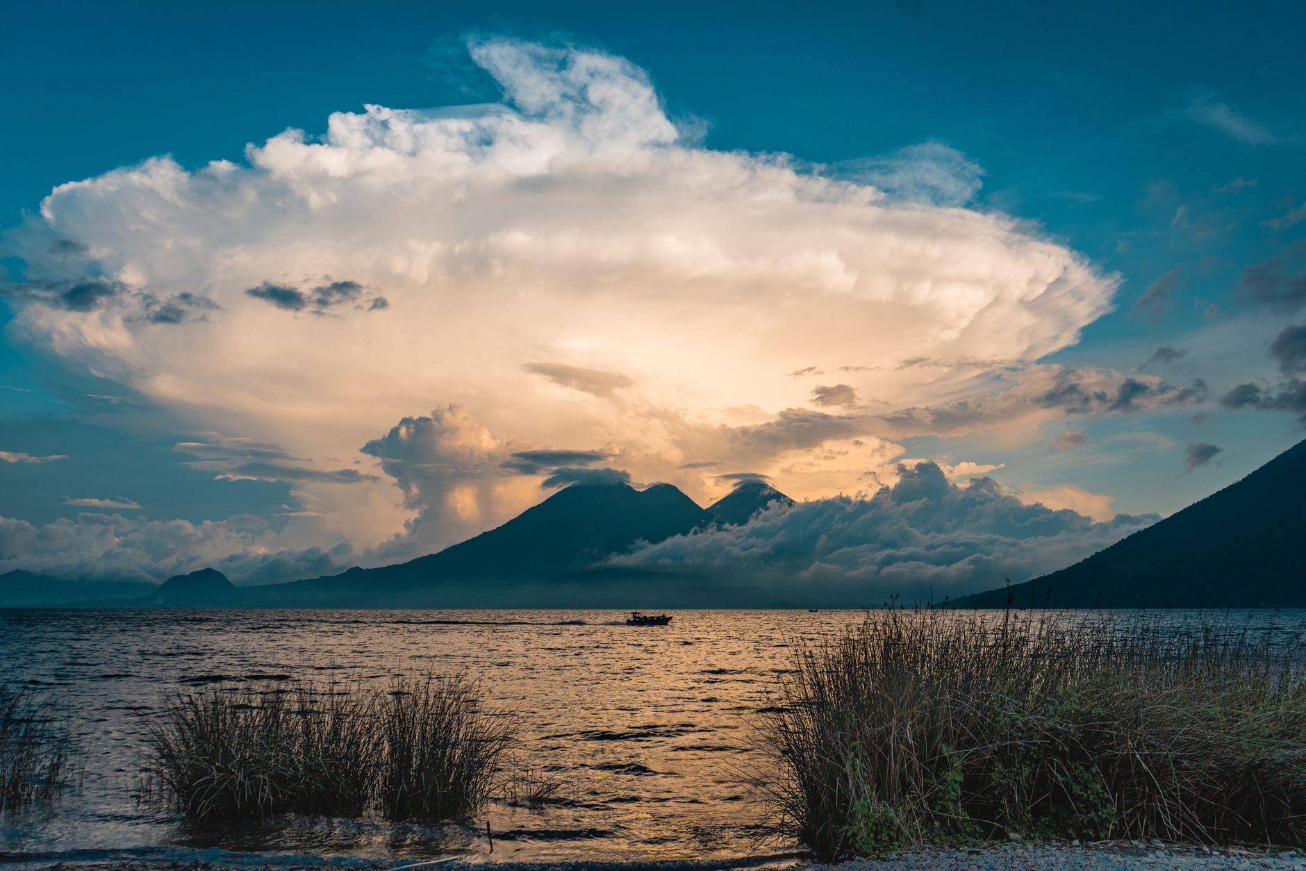 Sopečné jezero Atitlán v Guatemale s třemi vulkány na obzoru za hladinou