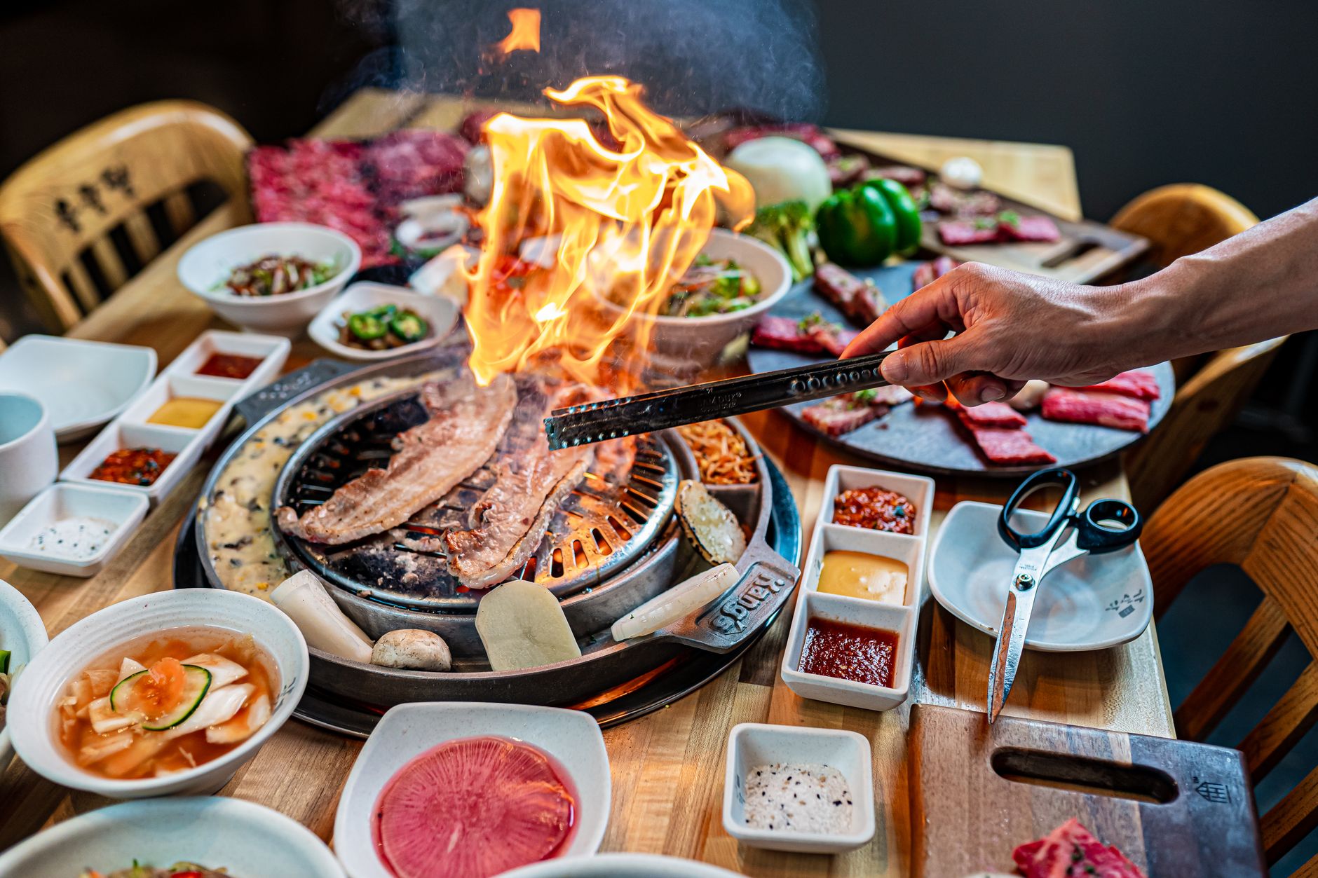 Korejské grilování na žhavém roštu s talíři příloh banchan a salátovými listy
