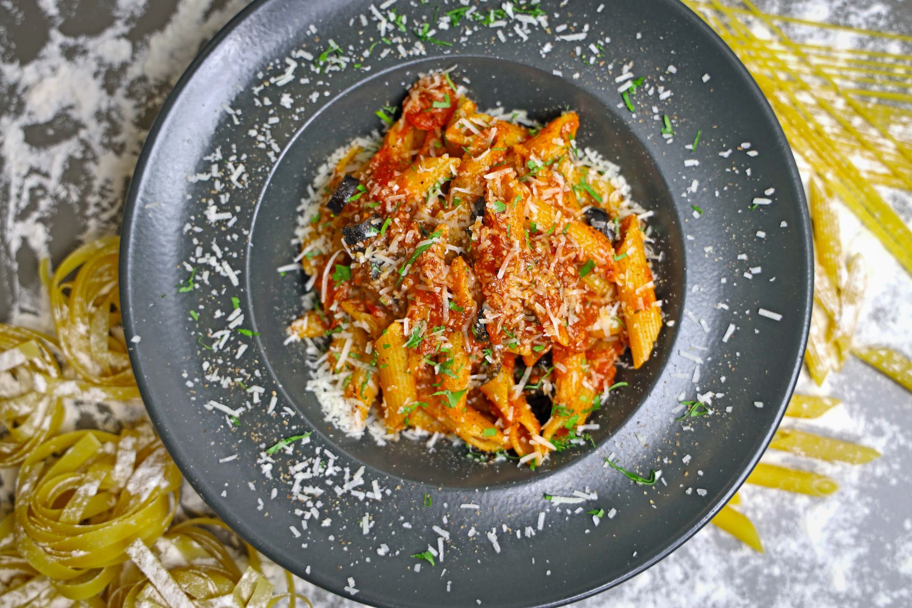 Talíř kalabrijských těstovin s pálivou klobásou nduja a sýrem na dřevěném stole