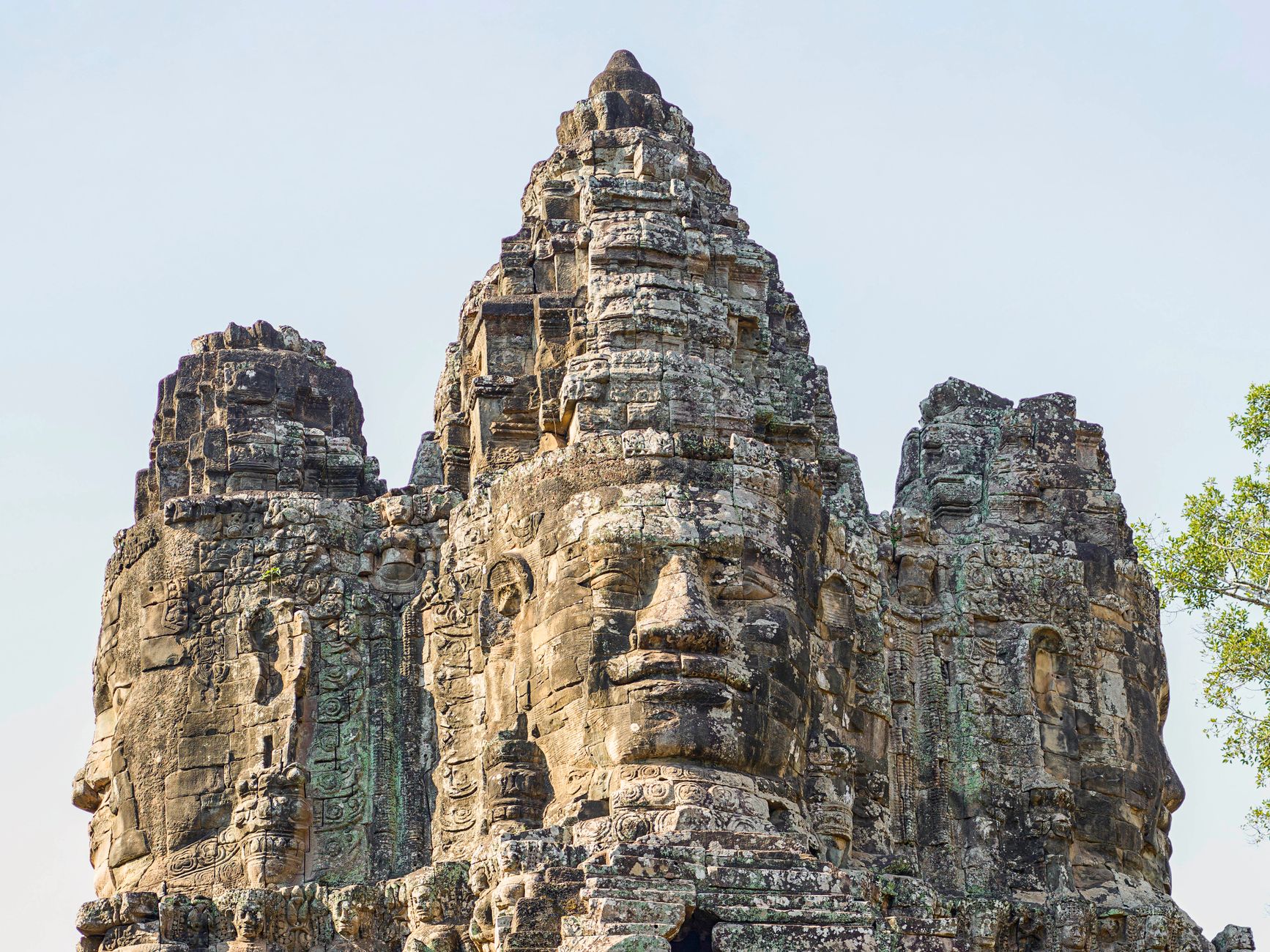 Kamenné tváře chrámu Bayon v Angkor Thom obklopené džunglí v Kambodži