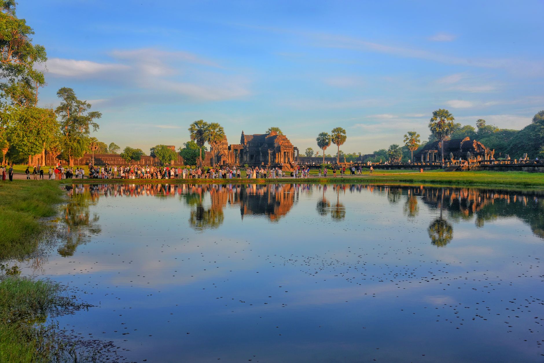 Chrámový komplex Angkor Wat za úsvitu se odráží na hladině jezírka v Kambodži