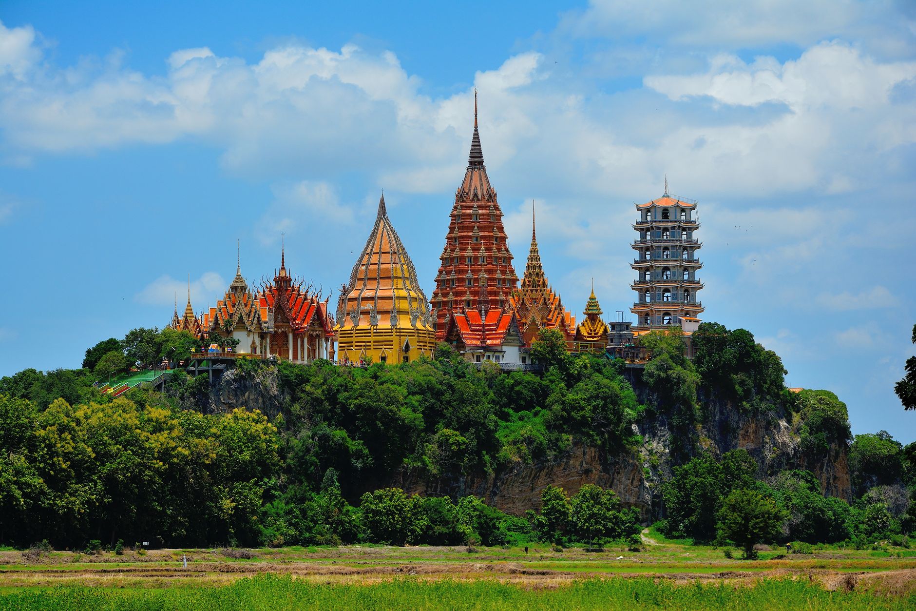 Zlatý Buddha a chrámová stavba Wat Tham Sua na kopci nad krajinou u Kanchanaburi
