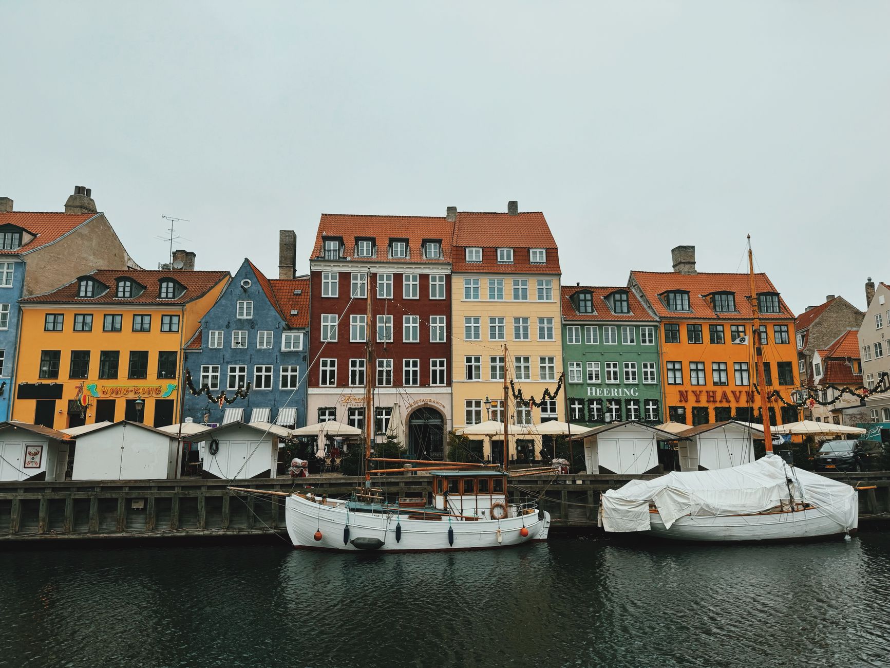 Barevné fasády domů a historické plachetnice podél kanálu Nyhavn v Kodani