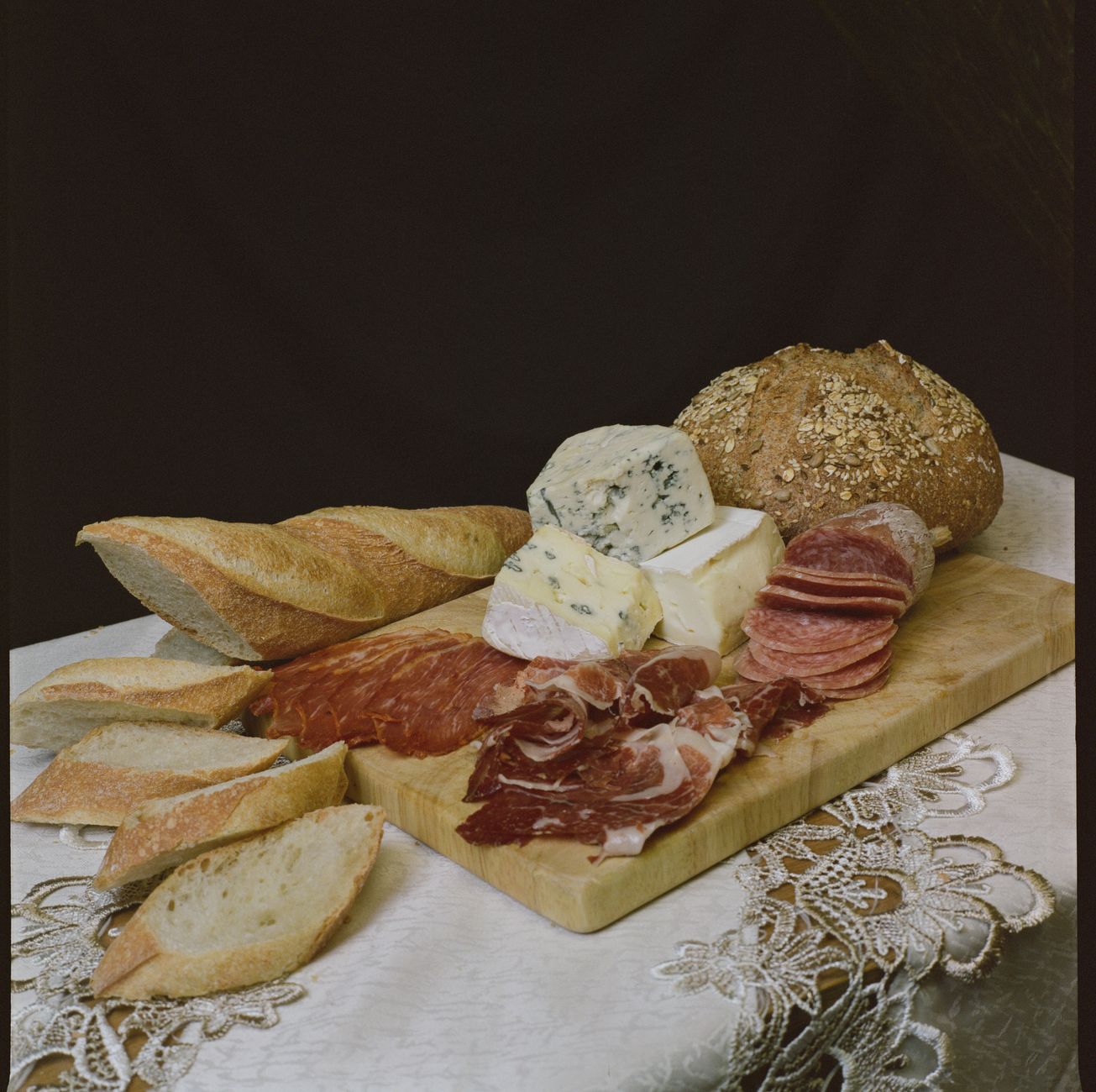 Talíř korsické charcuterie s uzeninami, ovčím sýrem a chlebem na dřevěném stole